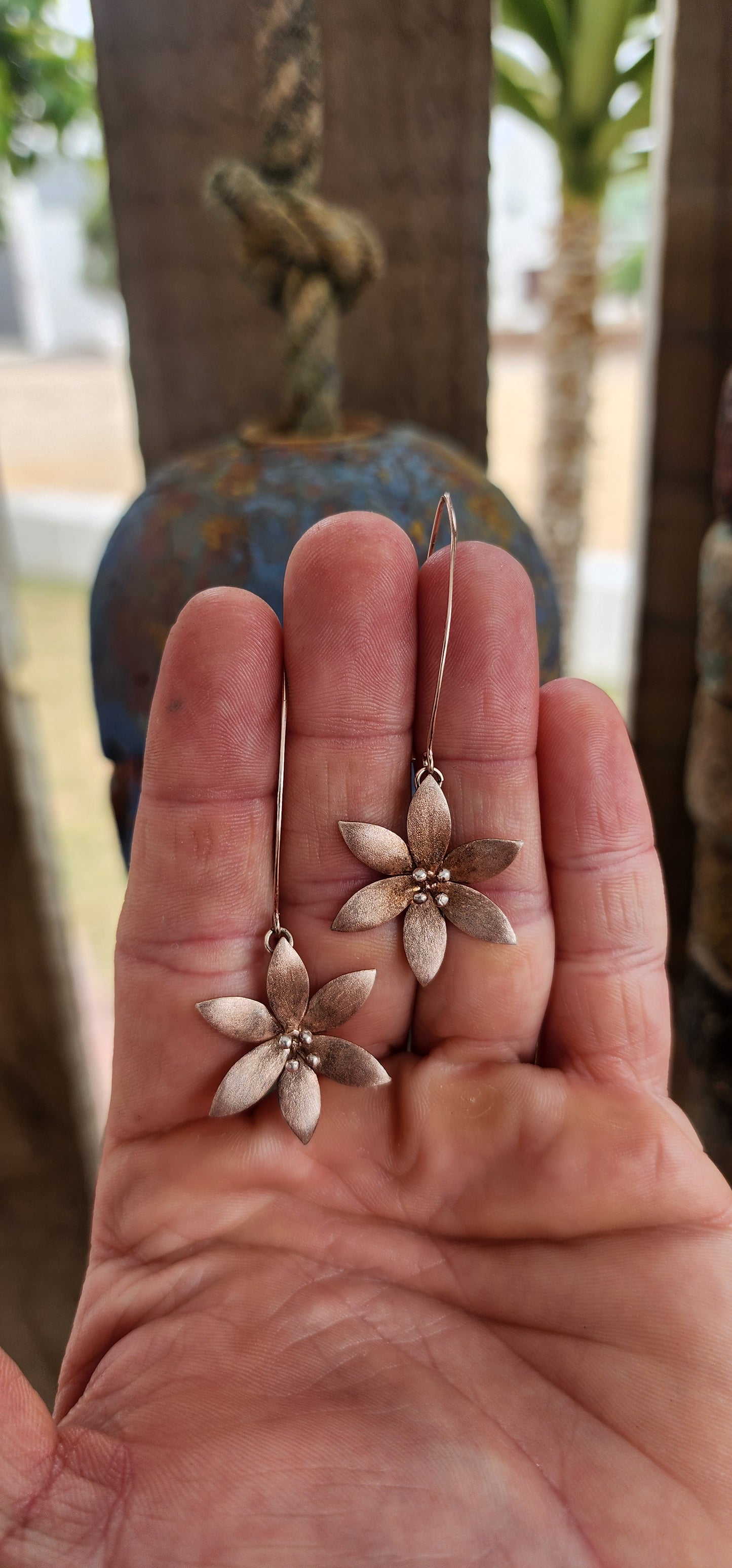 Crafted in sterling silver and finished with a subtle rose-gold wash, these flower drop earrings glow with a warm, romantic hue rather than a high-shine flash.