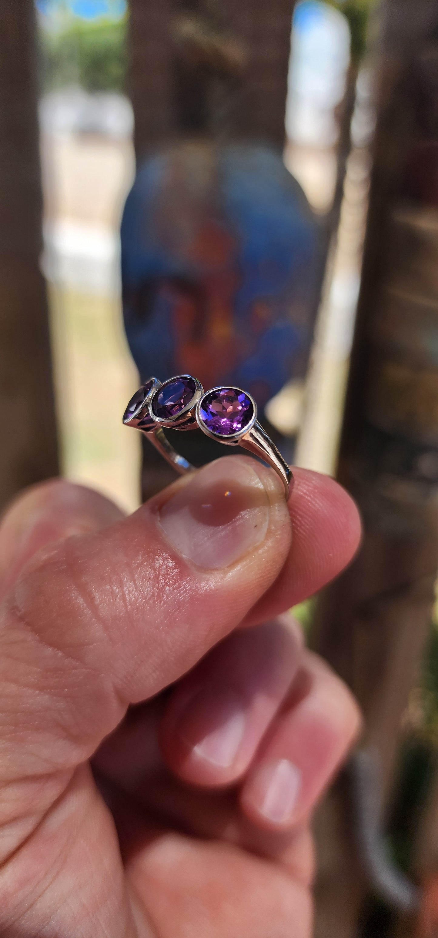 This sterling silver trilogy ring is a dreamy celebration of amethyst magic, set with three round faceted amethyst gemstones that glow in juicy shades of violet, plum and royal purple.
