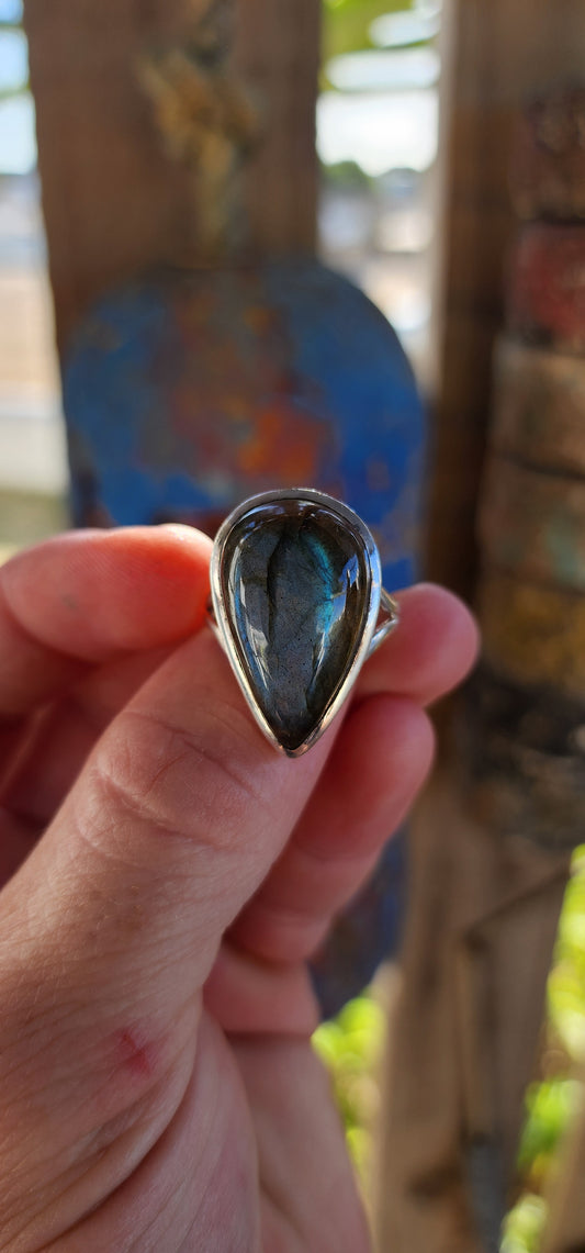A true mystic show-stopper — this enchanting, chunky artisan-made sterling silver cocktail ring features a generously sized pear-cut labradorite gemstone, bezel set in a sleek, sculptural frame that hugs the stone like liquid silver.