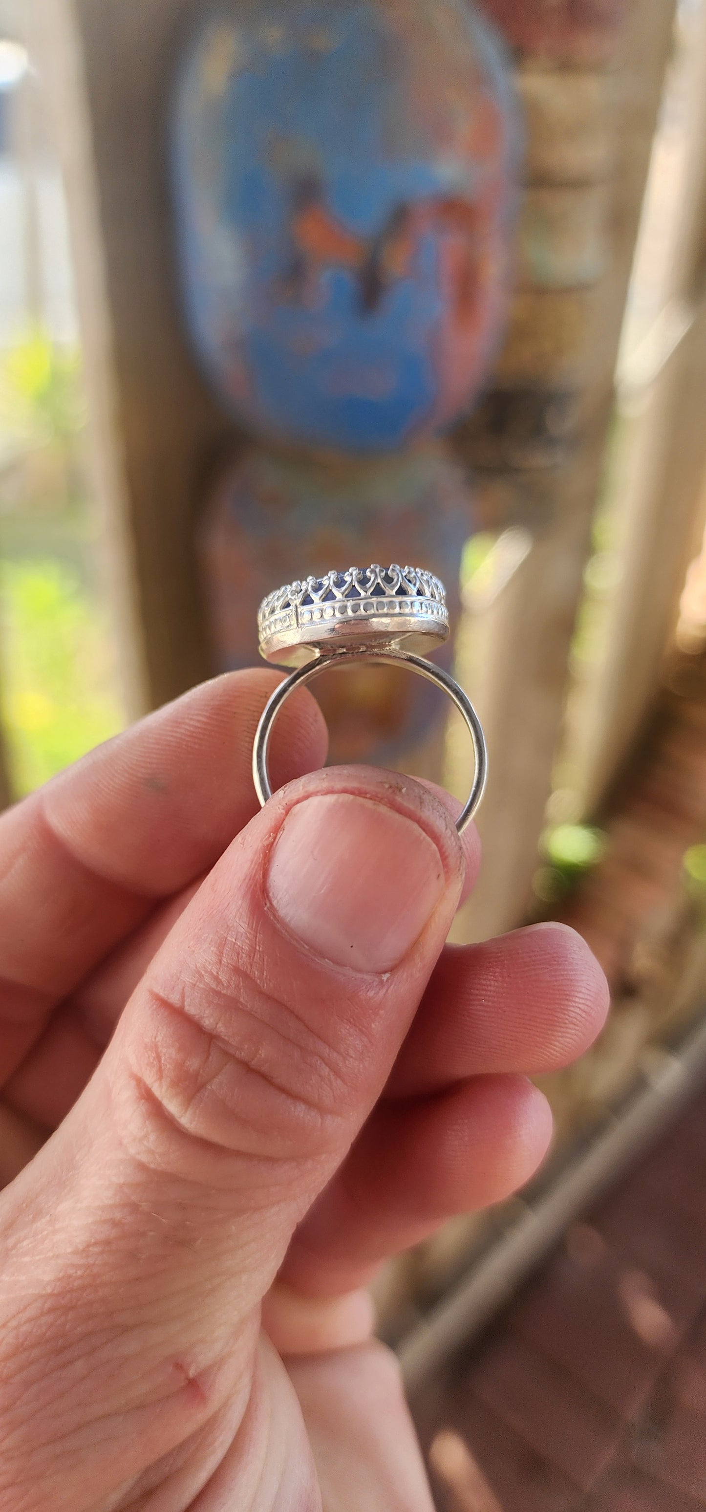 This artisan made sterling silver ring features a tumbled, organic-shaped blue sodalite gemstone, bezel-like cradled in ornate decorative claw prongs that look like a little crown around the stone.