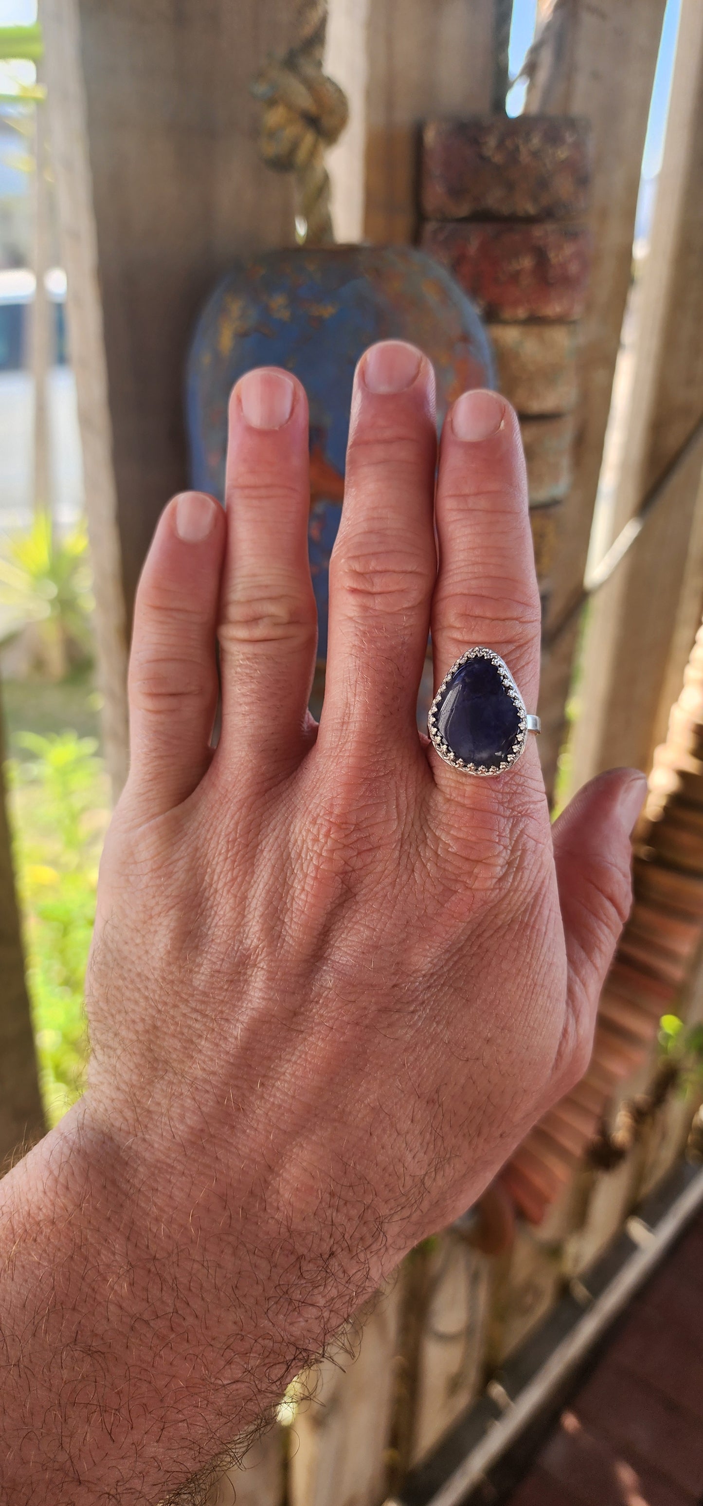 This artisan made sterling silver ring features a tumbled, organic-shaped blue sodalite gemstone, bezel-like cradled in ornate decorative claw prongs that look like a little crown around the stone.