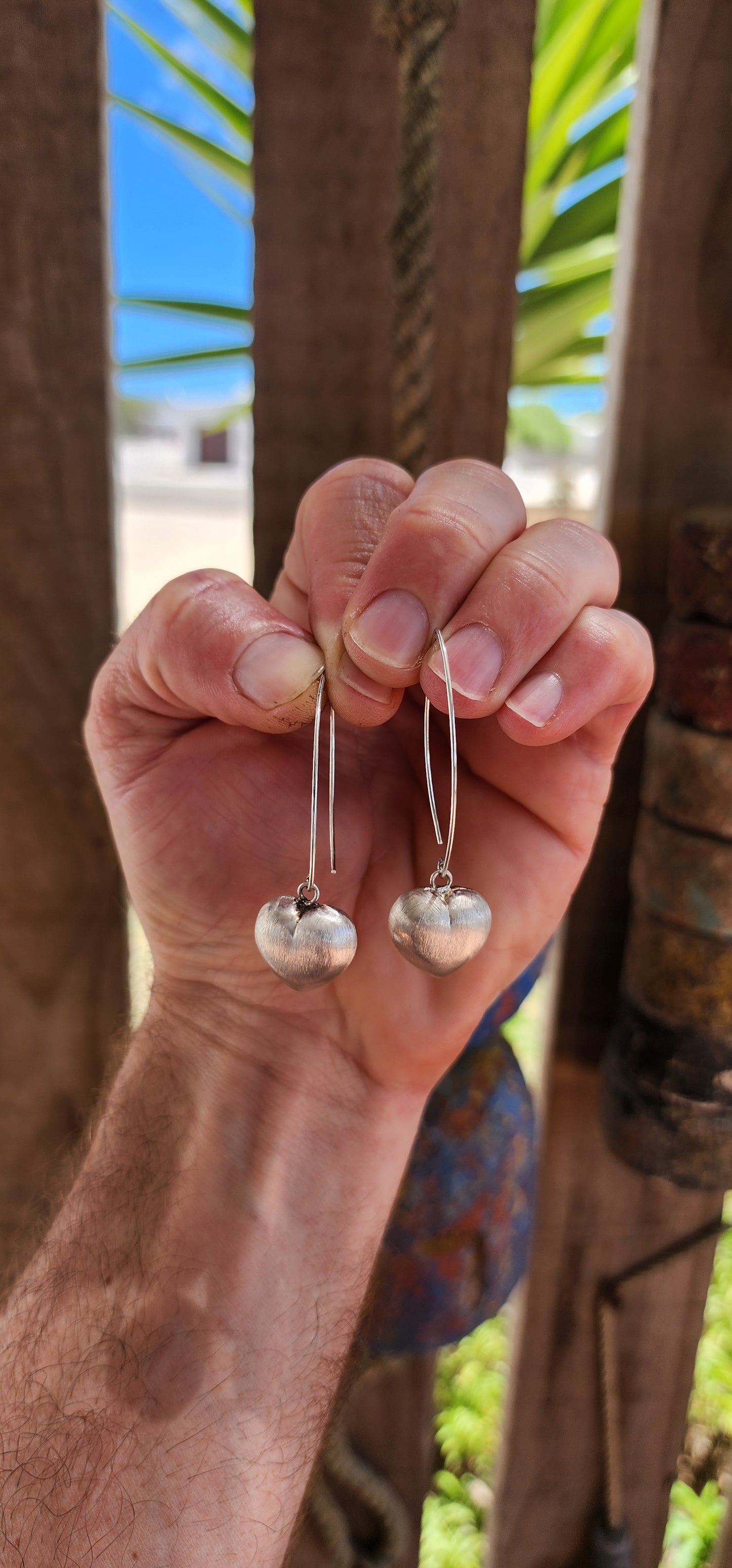 Sweet, but with presence. These sterling silver dangle drop earrings feature beautifully generous-sized puffed heart charms suspended from sleek shepherd hook wires.