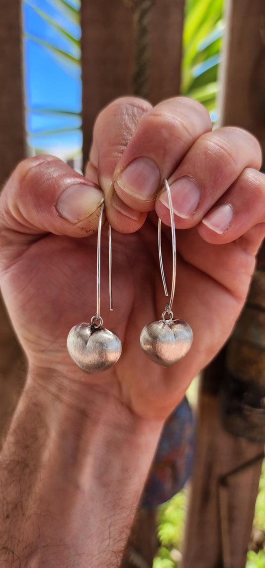 Sweet, but with presence. These sterling silver dangle drop earrings feature beautifully generous-sized puffed heart charms suspended from sleek shepherd hook wires.