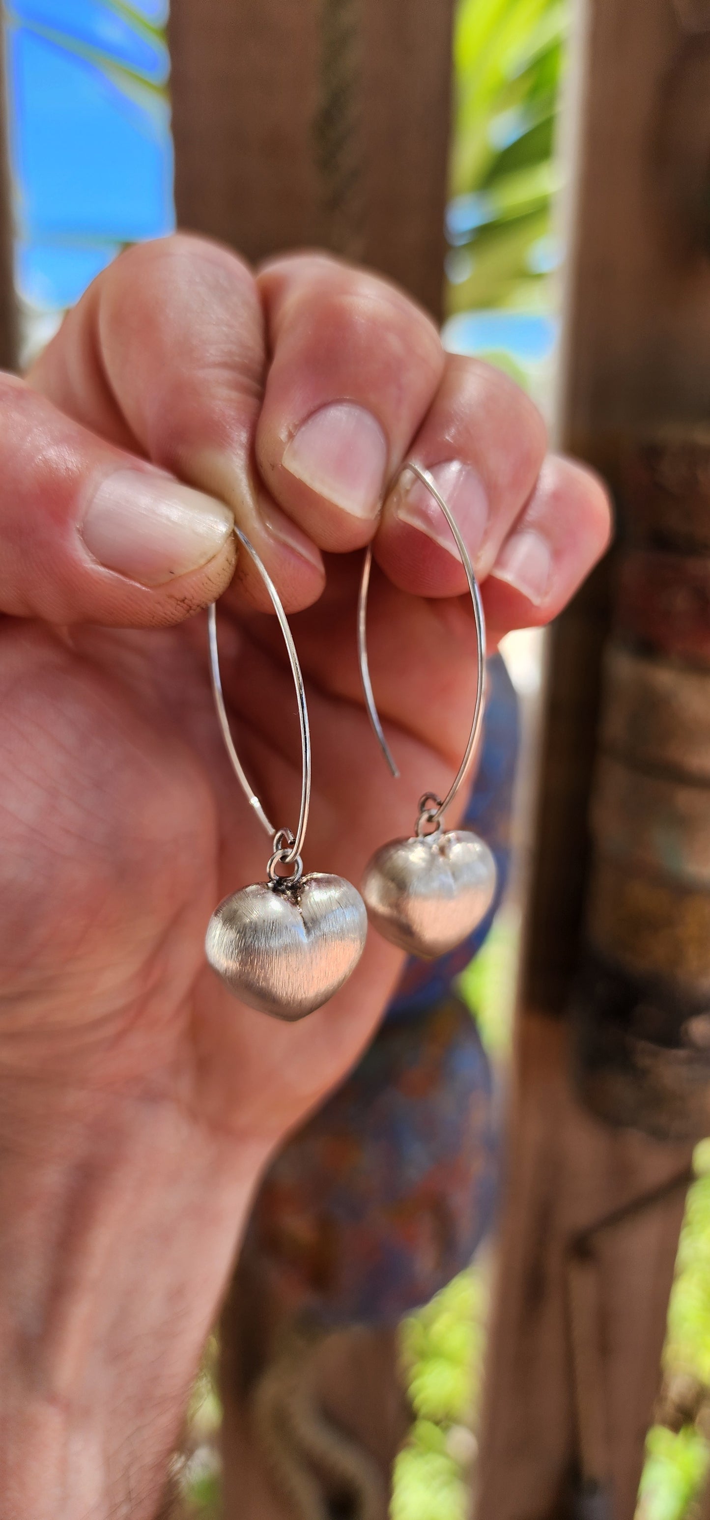 Sweet, but with presence. These sterling silver dangle drop earrings feature beautifully generous-sized puffed heart charms suspended from sleek shepherd hook wires.