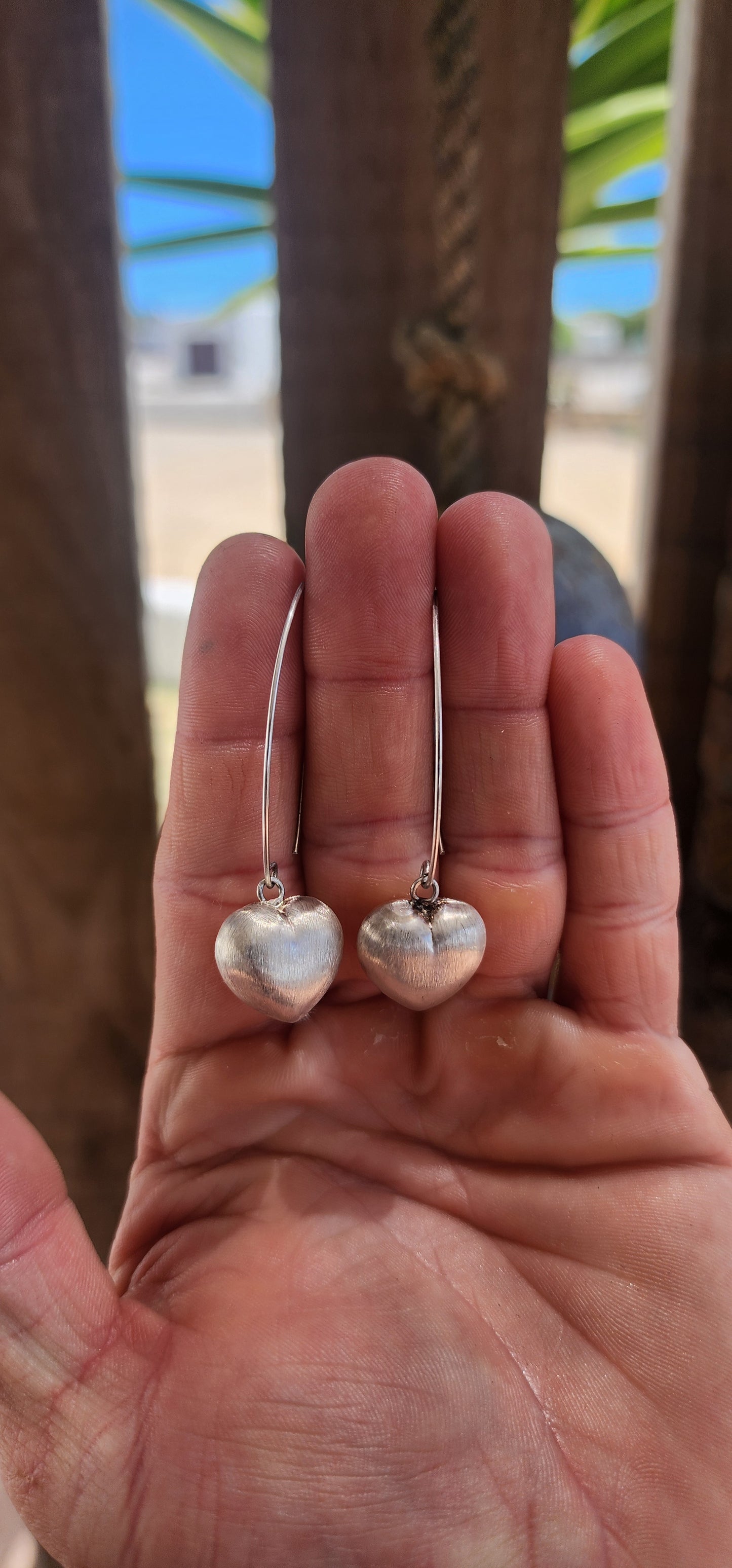 Sweet, but with presence. These sterling silver dangle drop earrings feature beautifully generous-sized puffed heart charms suspended from sleek shepherd hook wires.