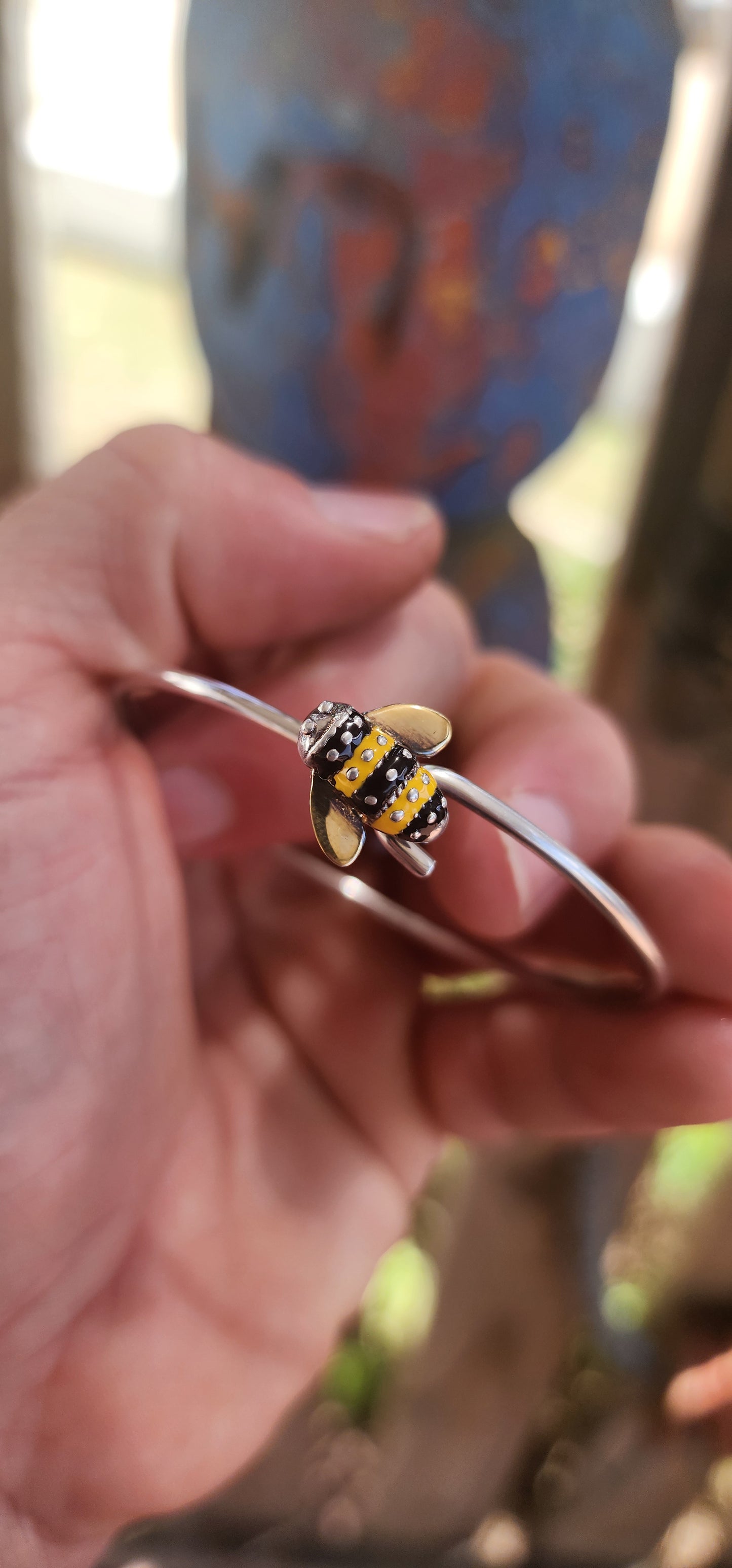 A charming designer sterling silver clip bangle by Daisy London, featuring the sweetest little enamelled bee perched at the centre.