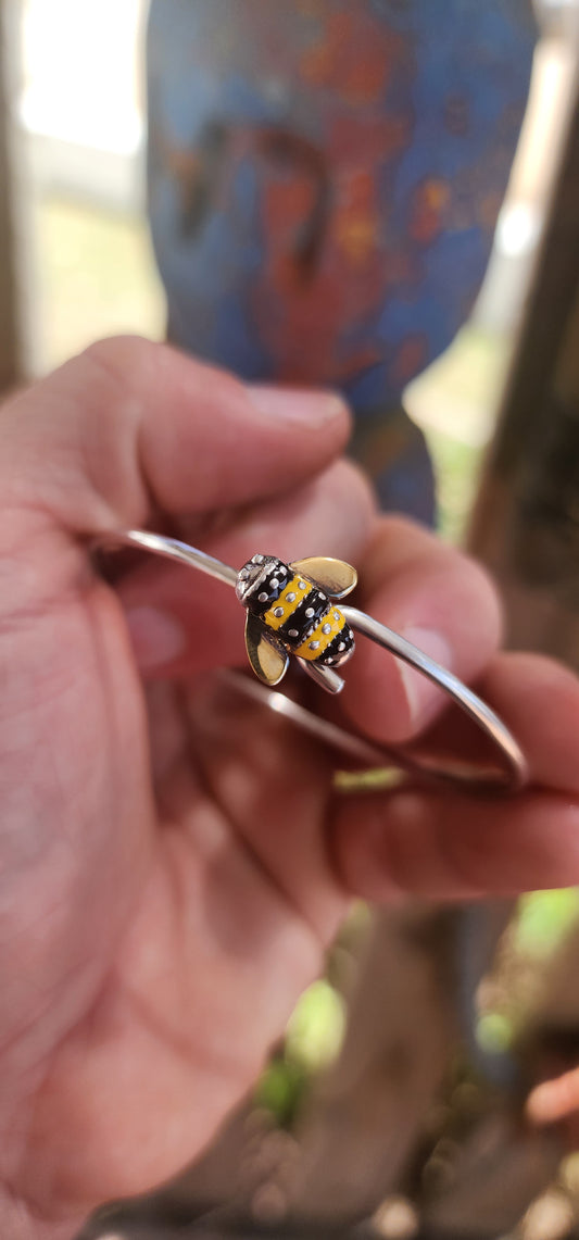 A charming designer sterling silver clip bangle by Daisy London, featuring the sweetest little enamelled bee perched at the centre.