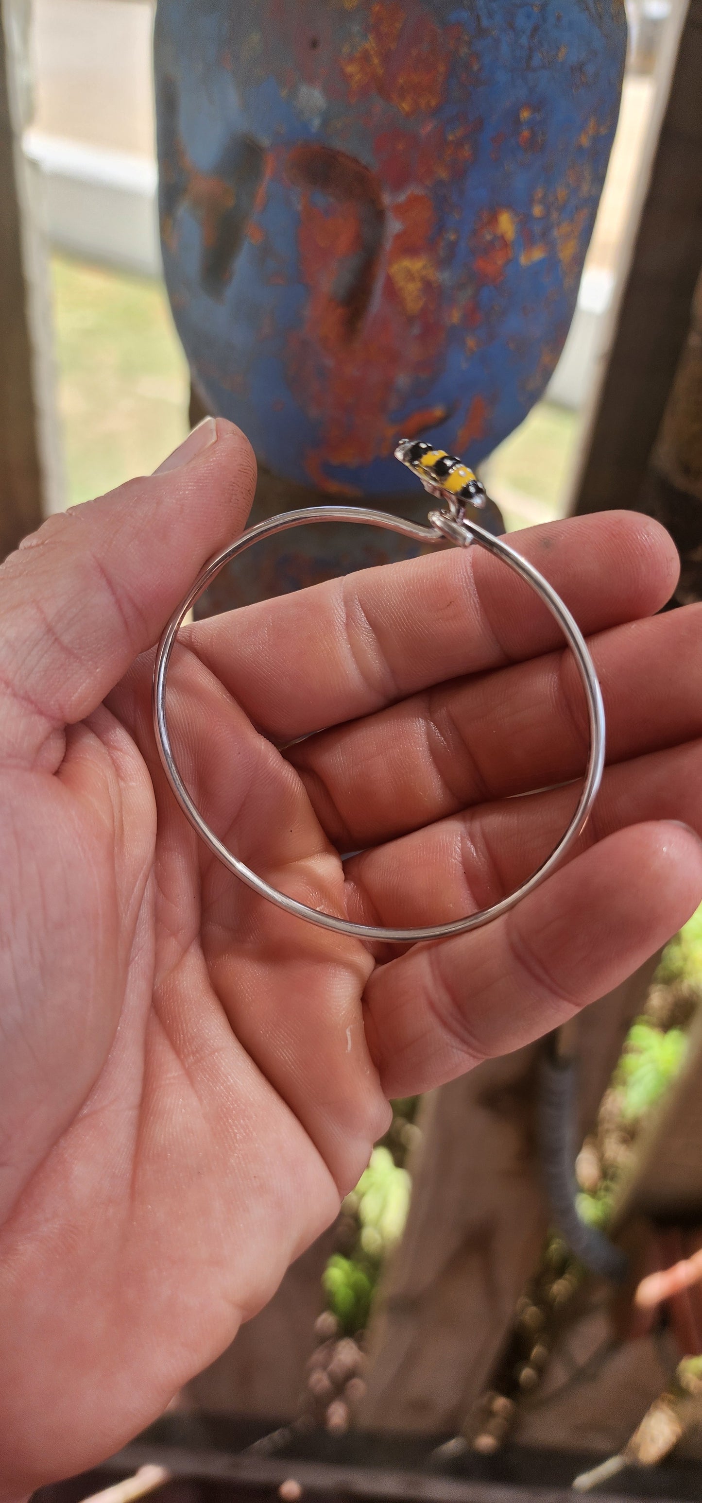 A charming designer sterling silver clip bangle by Daisy London, featuring the sweetest little enamelled bee perched at the centre.