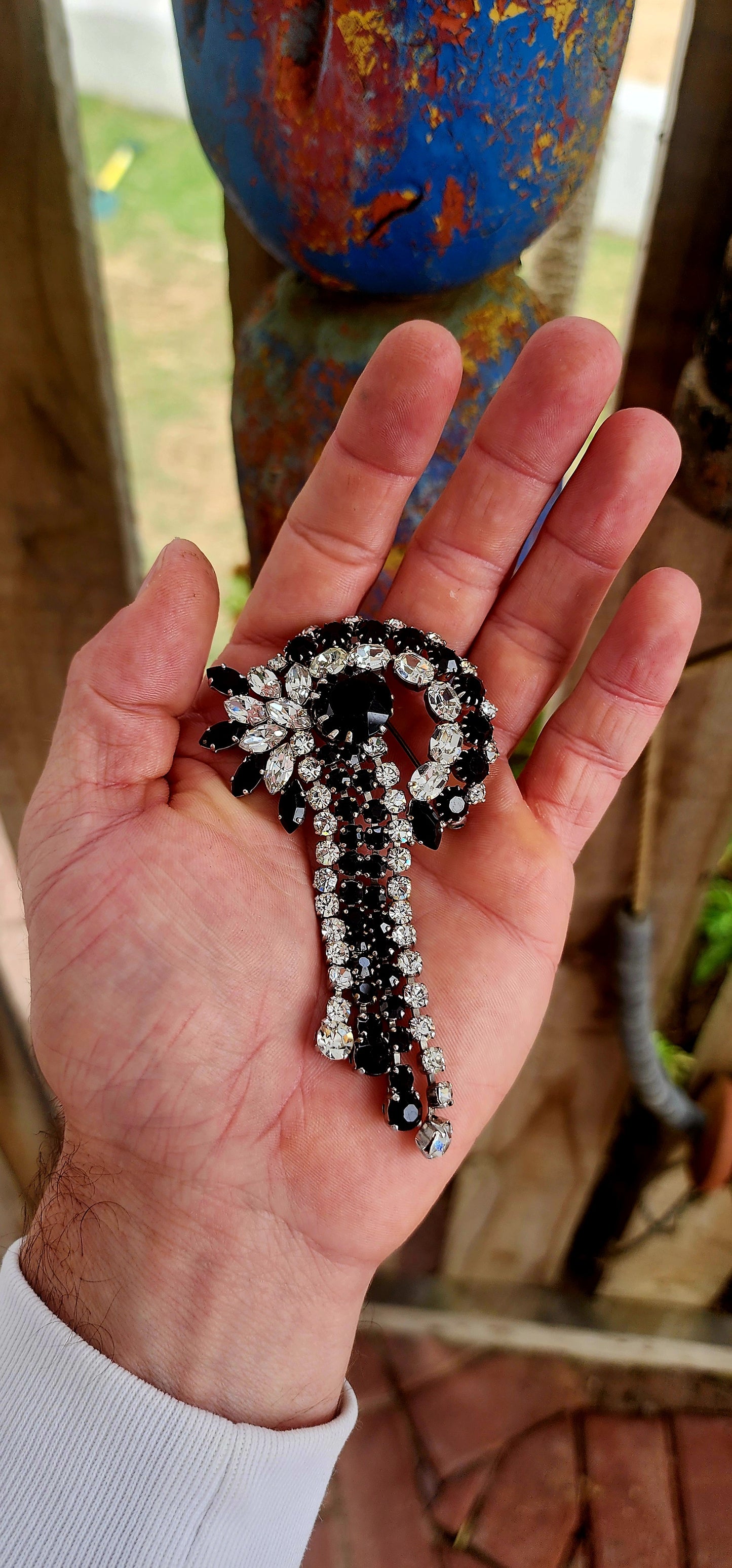 This breathtaking Art Deco era brooch is an absolute showstopper — crafted in silvertone metal and lavishly adorned with prong-set crystal rhinestones in striking shades of jet black and brilliant clear..