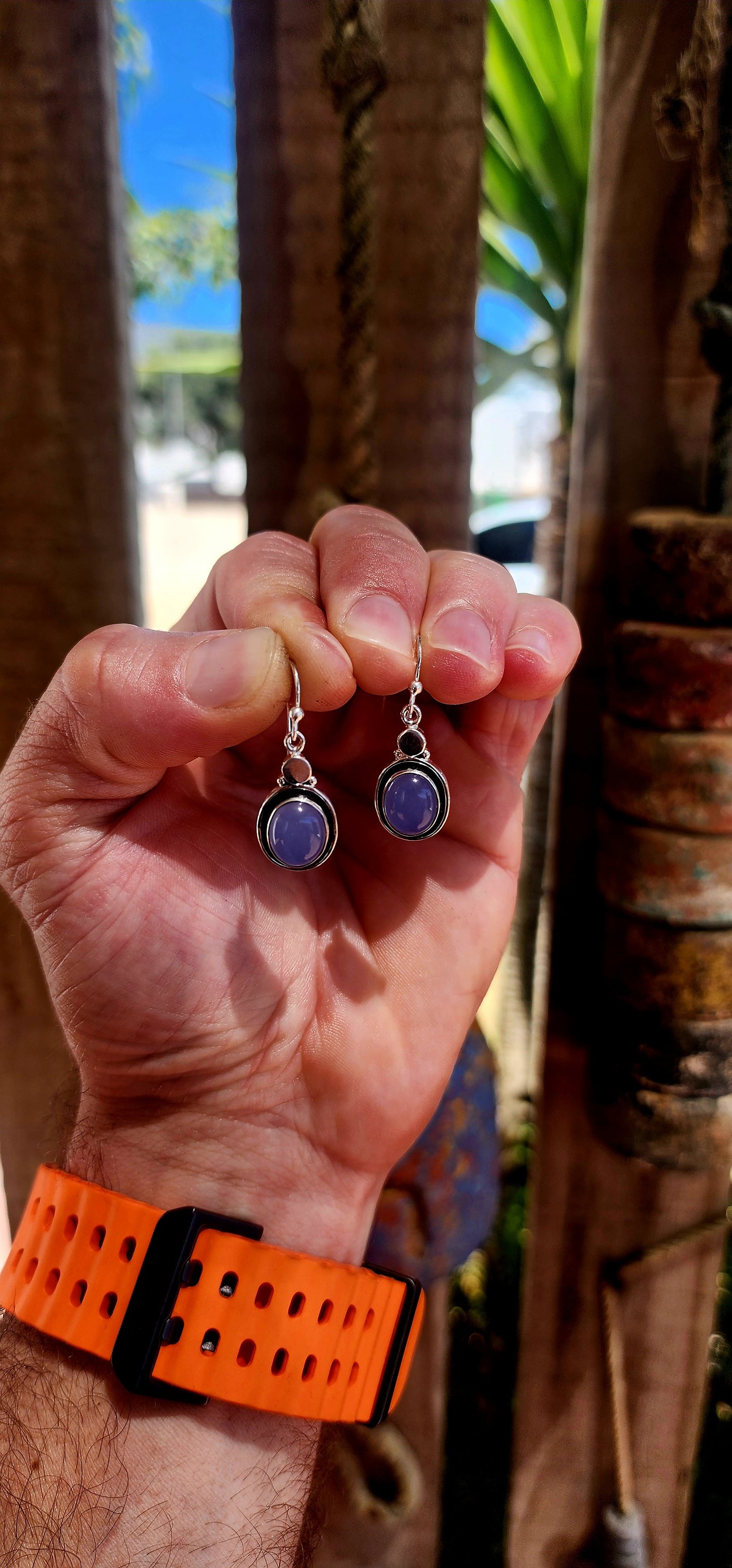 This artisan-made pair of sterling silver drop earrings features smooth, oval lavender-blue chalcedony cabochons, each beautifully tube-set in polished silver.