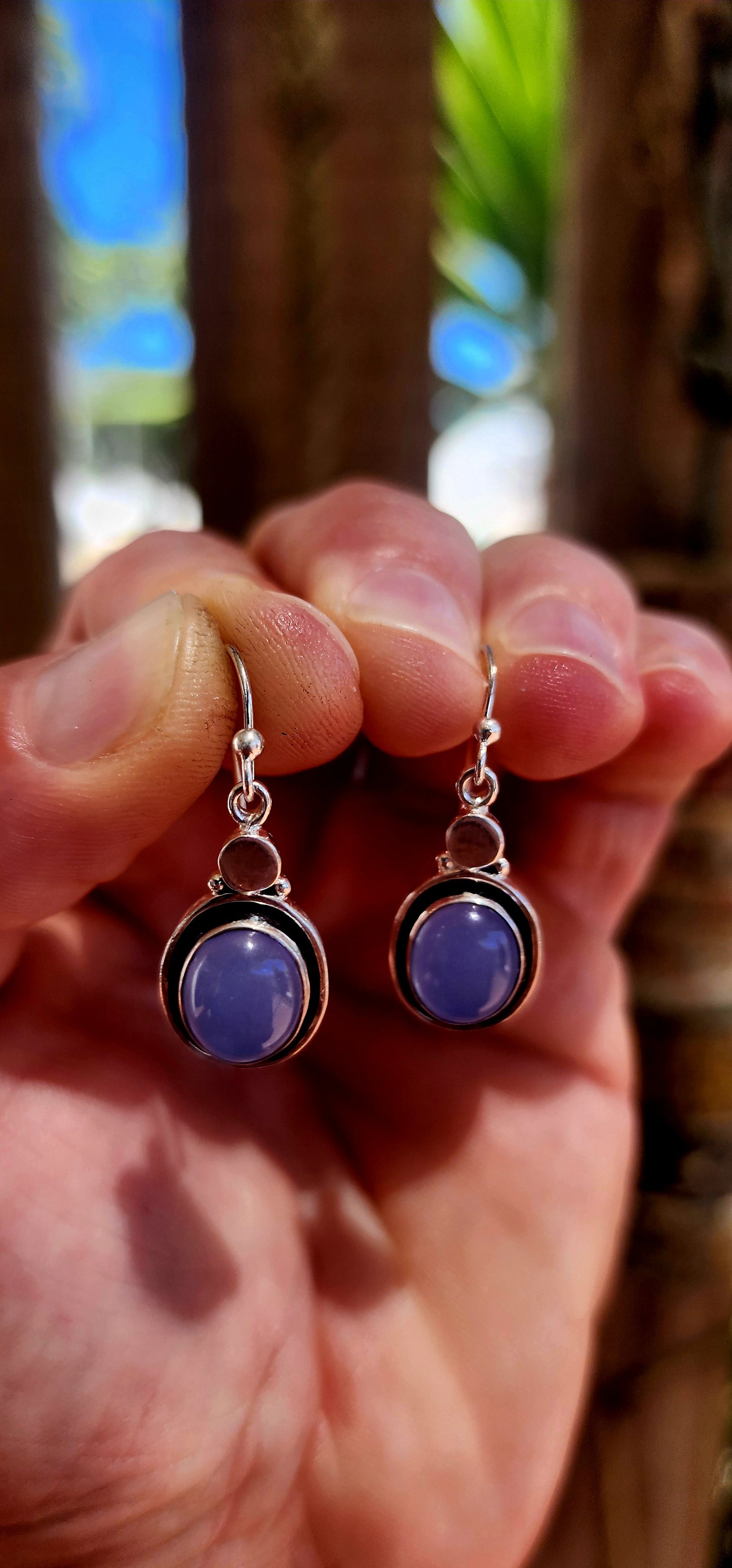 This artisan-made pair of sterling silver drop earrings features smooth, oval lavender-blue chalcedony cabochons, each beautifully tube-set in polished silver.