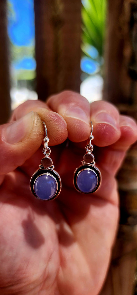 This artisan-made pair of sterling silver drop earrings features smooth, oval lavender-blue chalcedony cabochons, each beautifully tube-set in polished silver.