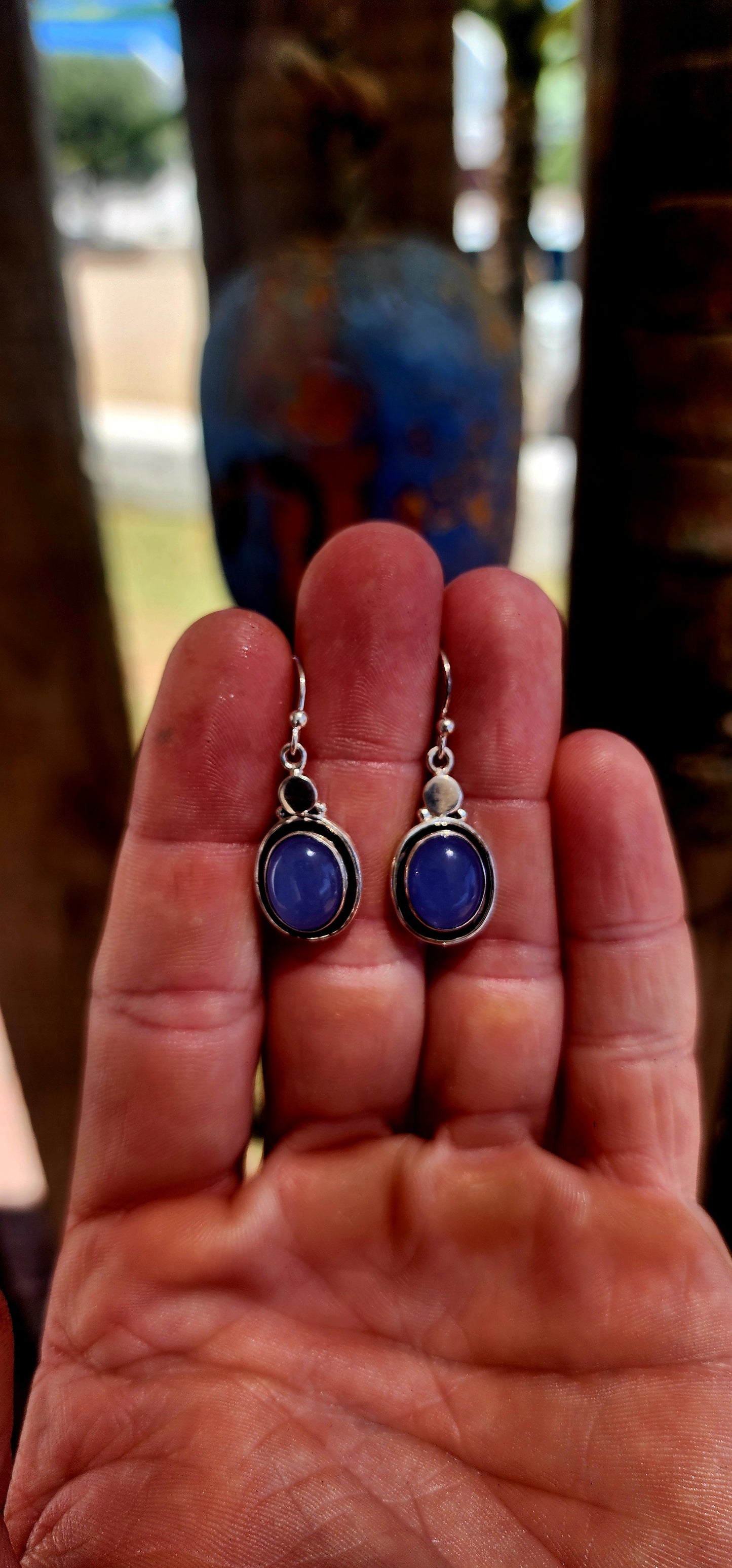 This artisan-made pair of sterling silver drop earrings features smooth, oval lavender-blue chalcedony cabochons, each beautifully tube-set in polished silver.
