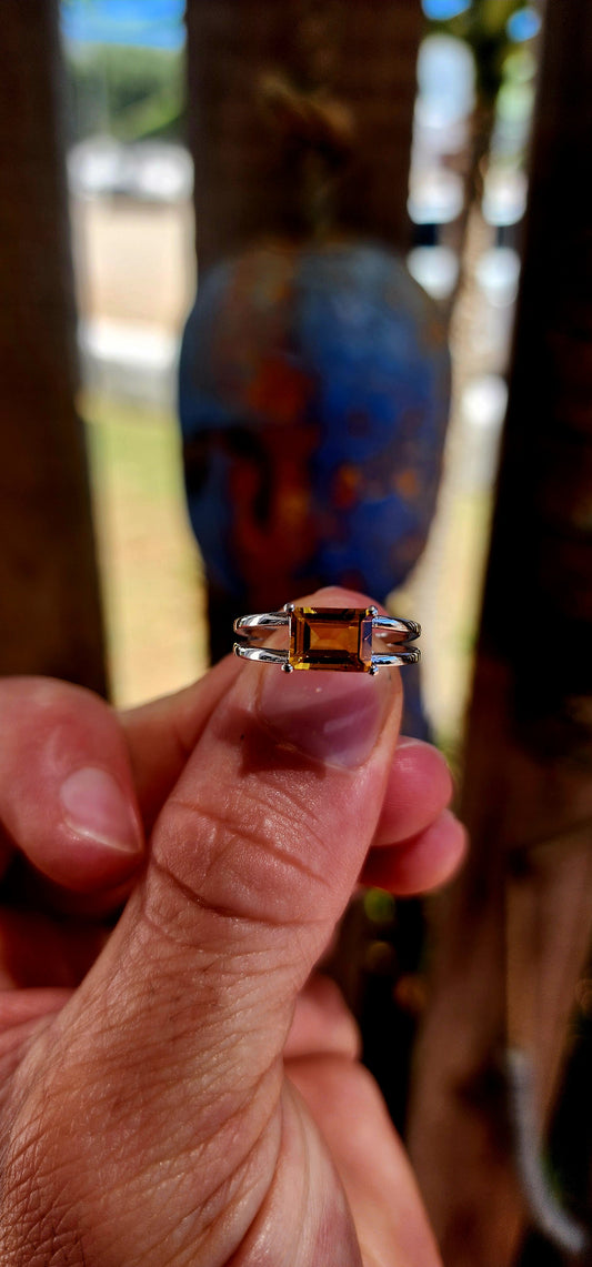 This beautiful sterling silver solitaire ring features a striking emerald-cut citrine, glowing in rich golden-orange tones.