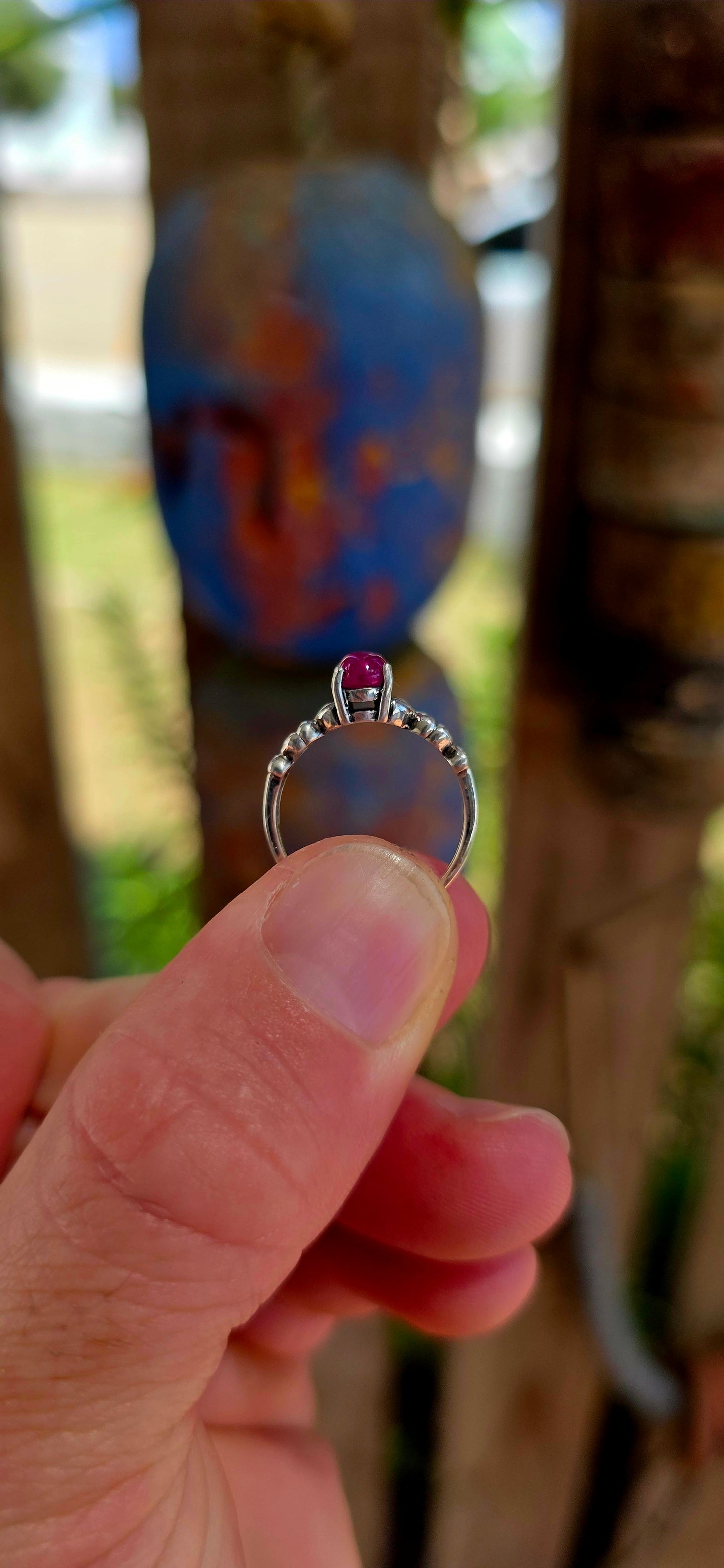 This beautiful sterling silver solitaire-style ring features a glowing oval-cut ruby cabochon, prong-set proudly at the centre