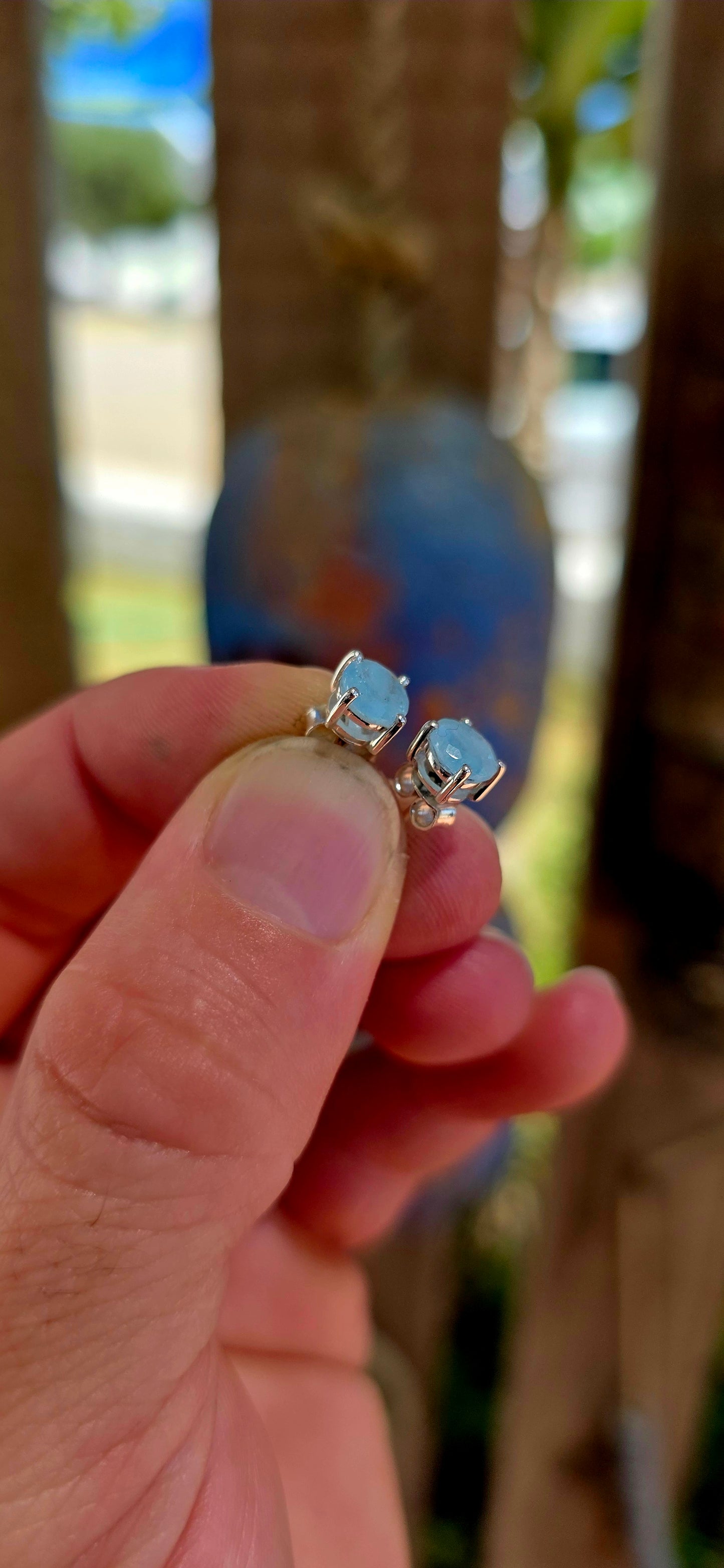 This striking pair of unisex sterling silver stud earrings features round faceted aquamarine gemstones in a soft milky / opaque tone — giving them a dreamy, sea-glass quality rather than a fully transparent sparkle.