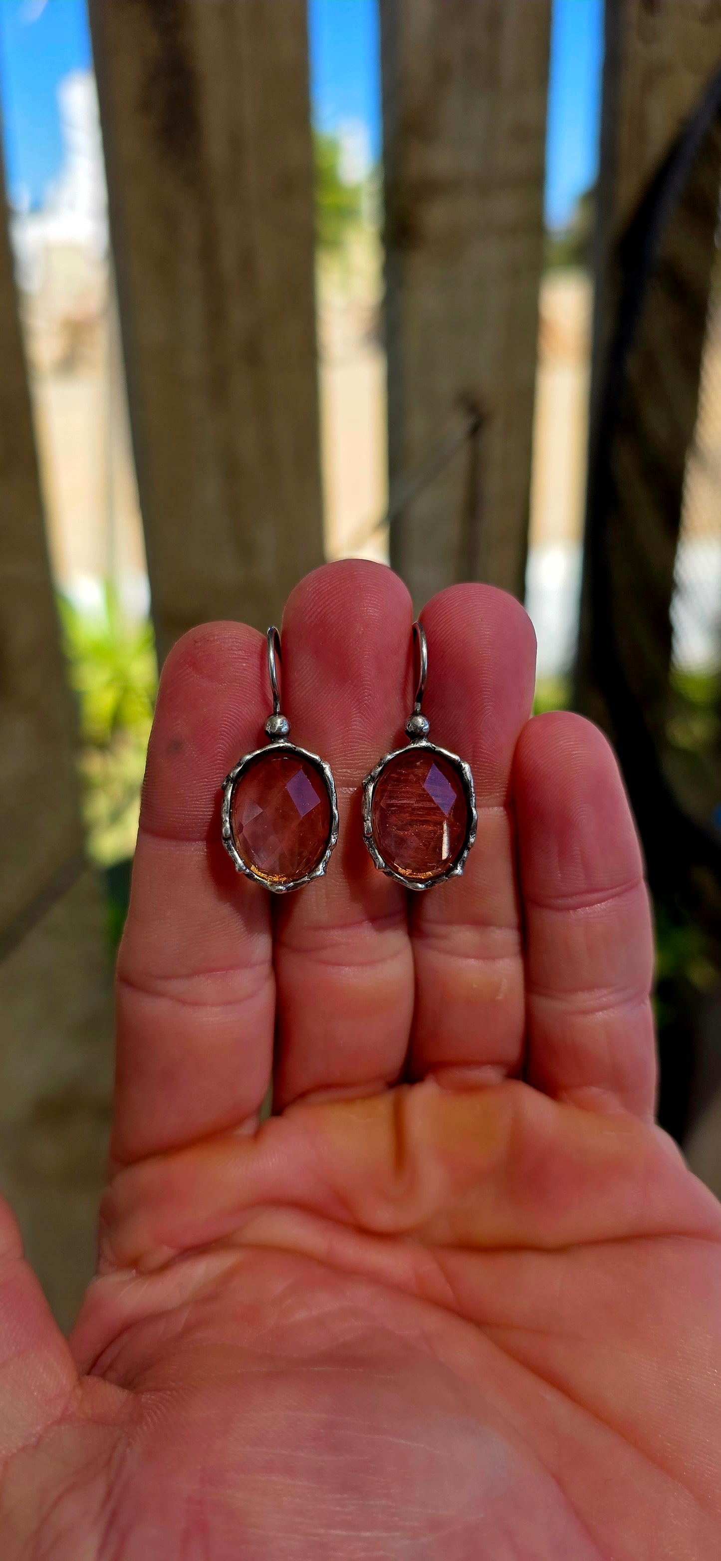 These beautiful artisan-made designer earrings are crafted in sterling silver and feature luminous faceted oval-cut strawberry quartz gemstones in a warm, soft rose hue.