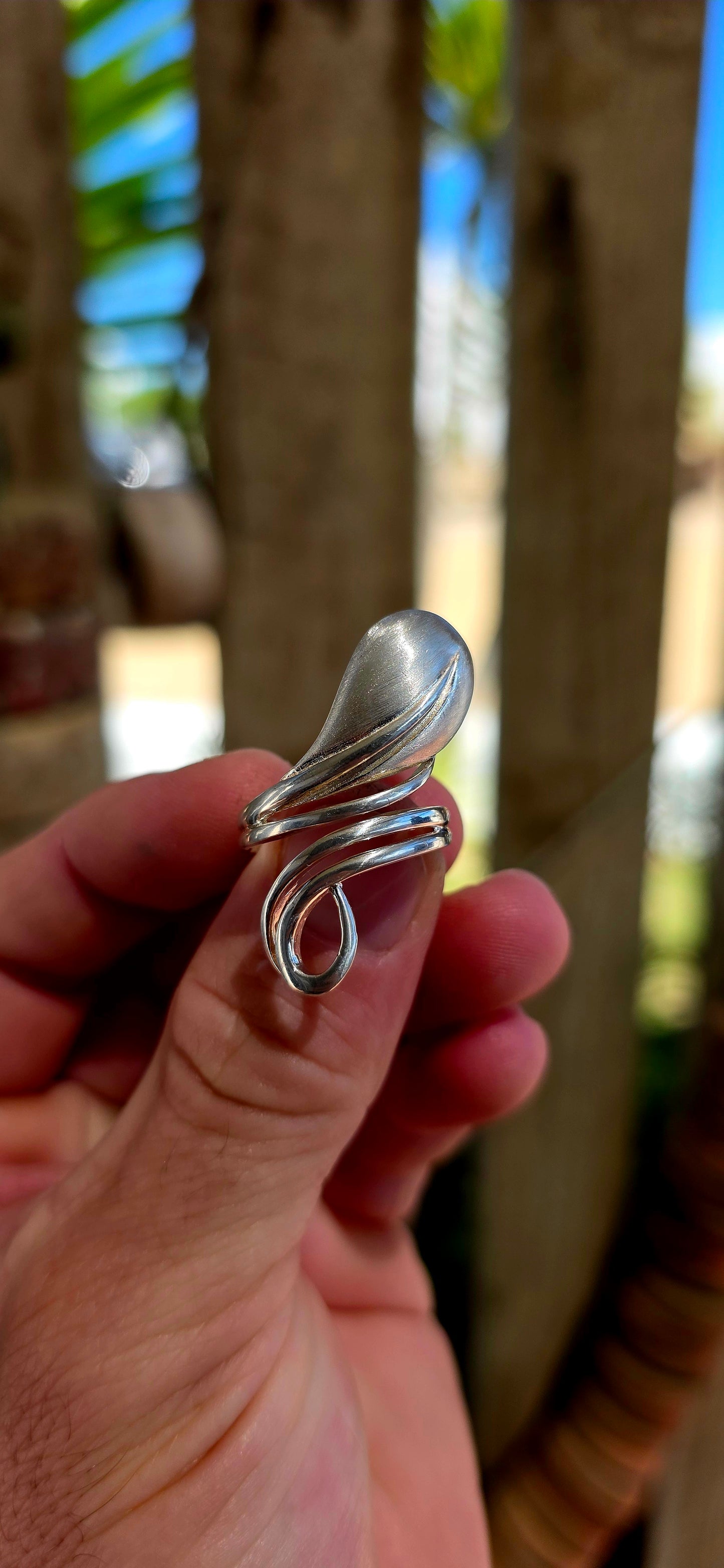 This striking artisan-made ring is crafted in solid sterling silver and designed in a dramatic modernist wrap style, where flowing silver forms curl gracefully around the finger like a ribbon of metal.
