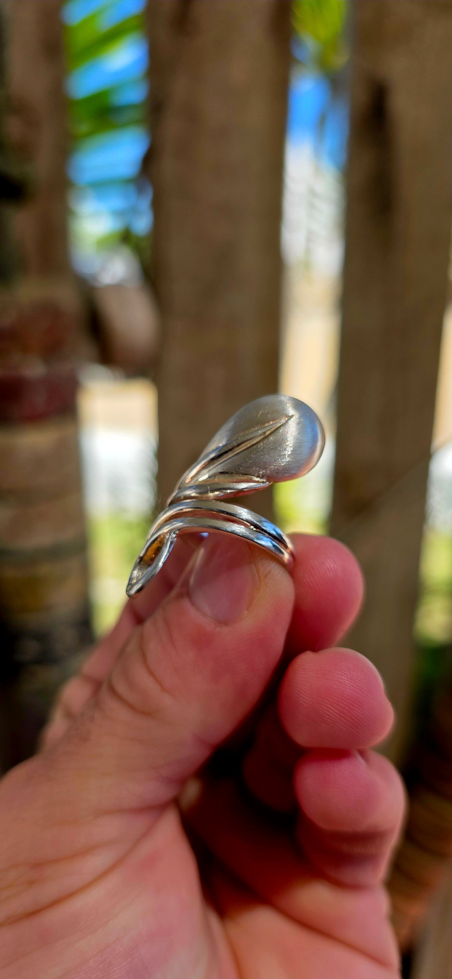 This striking artisan-made ring is crafted in solid sterling silver and designed in a dramatic modernist wrap style, where flowing silver forms curl gracefully around the finger like a ribbon of metal.