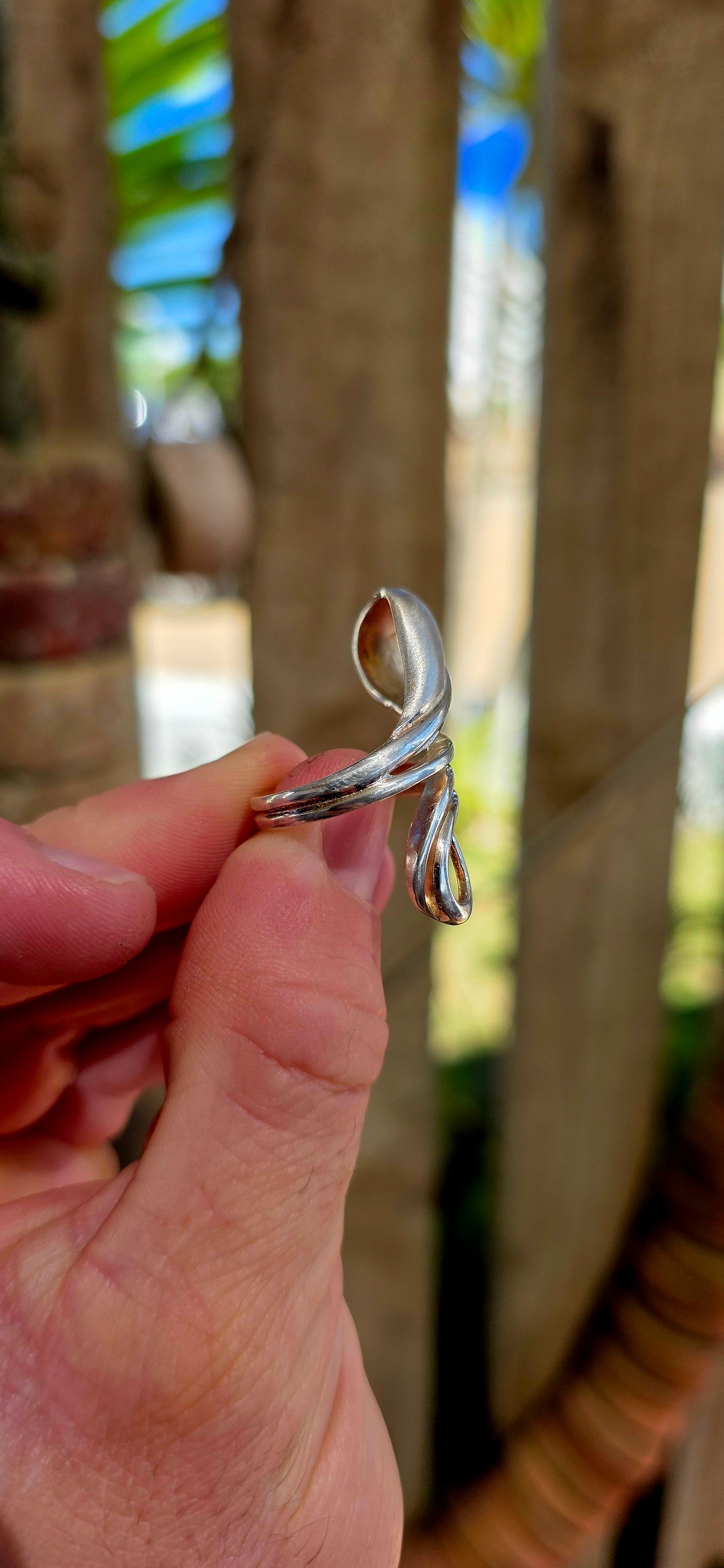 This striking artisan-made ring is crafted in solid sterling silver and designed in a dramatic modernist wrap style, where flowing silver forms curl gracefully around the finger like a ribbon of metal.