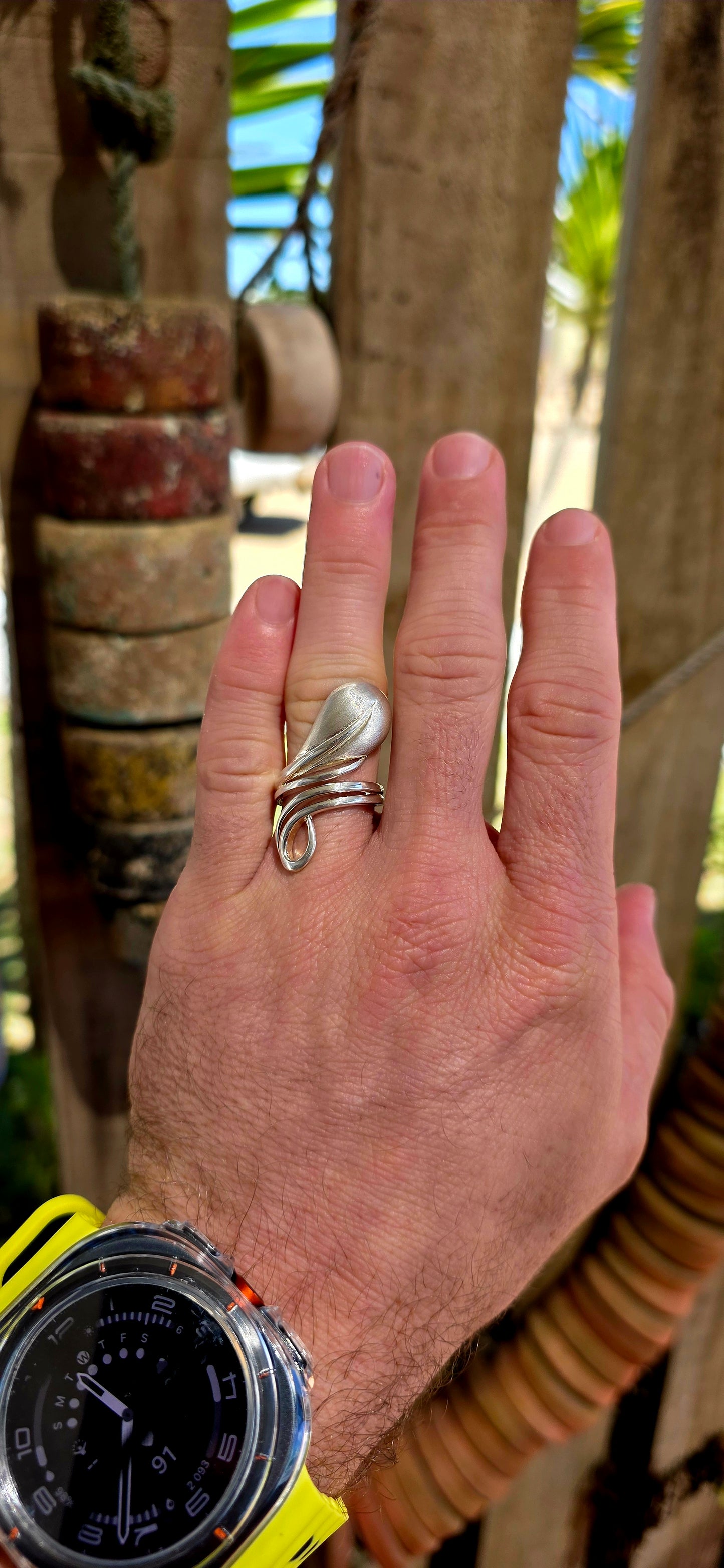 This striking artisan-made ring is crafted in solid sterling silver and designed in a dramatic modernist wrap style, where flowing silver forms curl gracefully around the finger like a ribbon of metal.