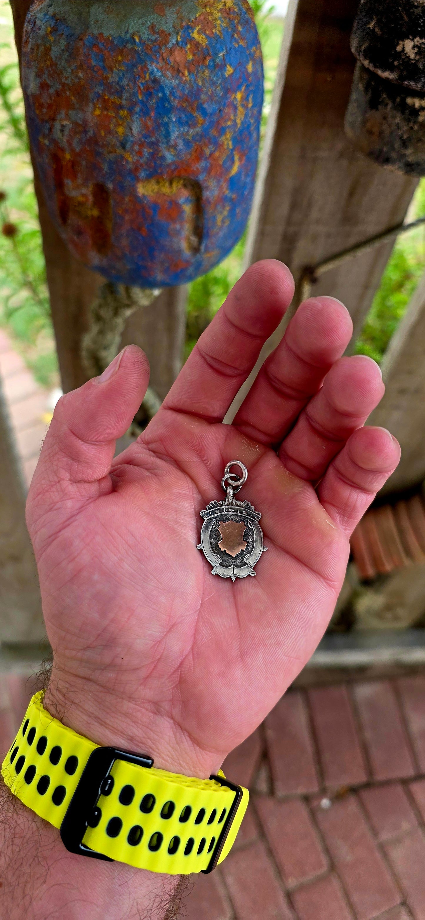 This beautiful antique shield fob pendant is crafted in hallmarked sterling silver, featuring a striking 9ct rose gold shield cartouche at its centre.
