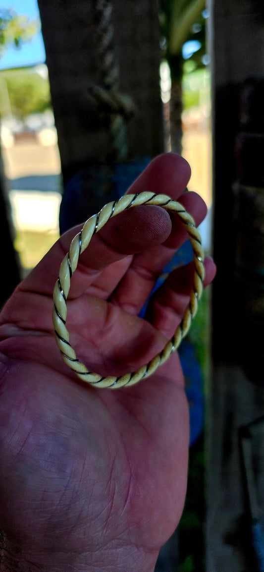 A beautiful antique hand-carved ivory bangle, crafted in a graceful twisted rope / swirl pattern and delicately wrapped with fine sterling silver wire that spirals along the entire circumference of the bracelet.