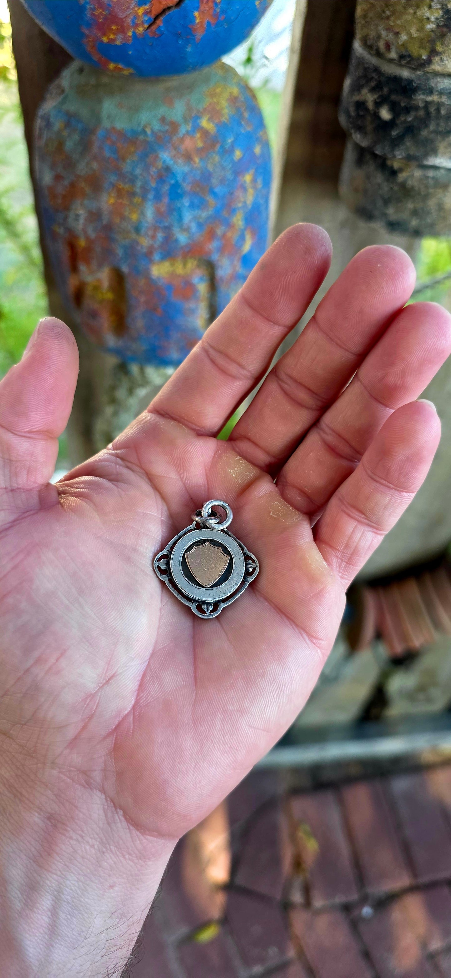 A beautiful antique hallmarked fob shield pendant, crafted in sterling silver and decorated with a raised 9ct rose gold shield cartouche, creating a striking and elegant two-tone contrast.