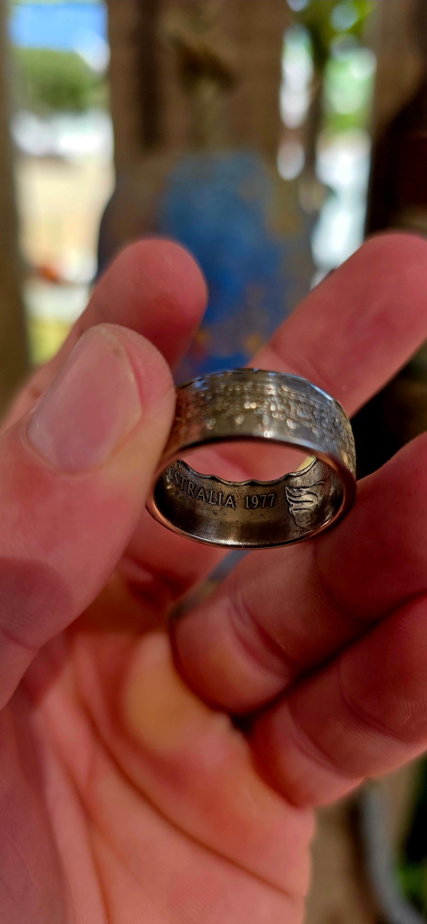 A bold, artisan-crafted coin ring, expertly formed from an authentic 1977 Australian 50 cent coin, struck in nickel and featuring Queen Elizabeth II.