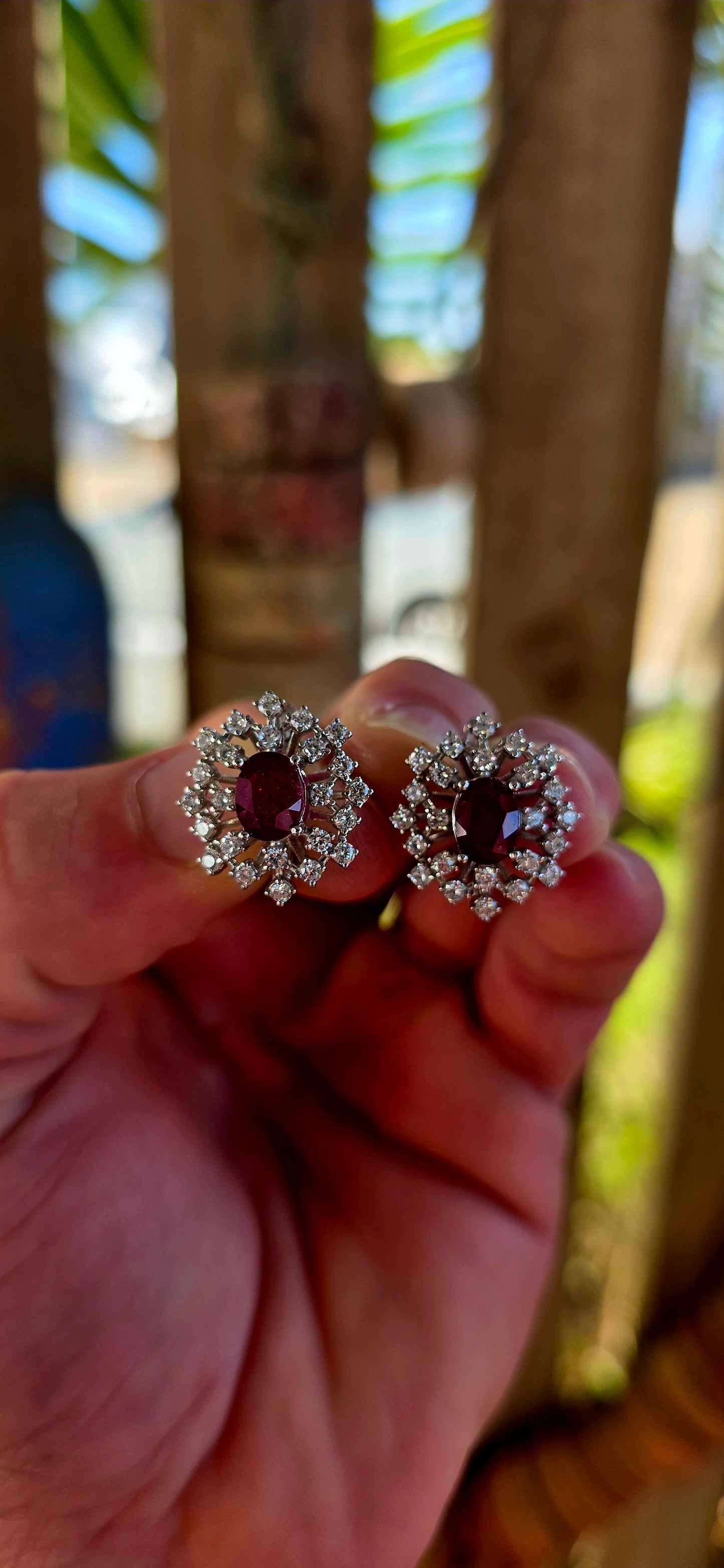 A striking pair of sterling silver starburst cluster earrings, designed to command attention from every angle. At the heart of each earring sits a rich oval-cut ruby, prong-set to let that deep, romantic red glow through beautifully.