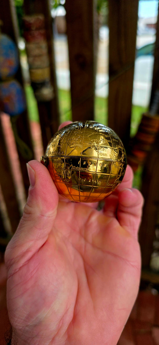 A wildly charming and highly sought-after mid-century novelty compact, beautifully crafted in warm golden brass — and shaped as a miniature world globe.
