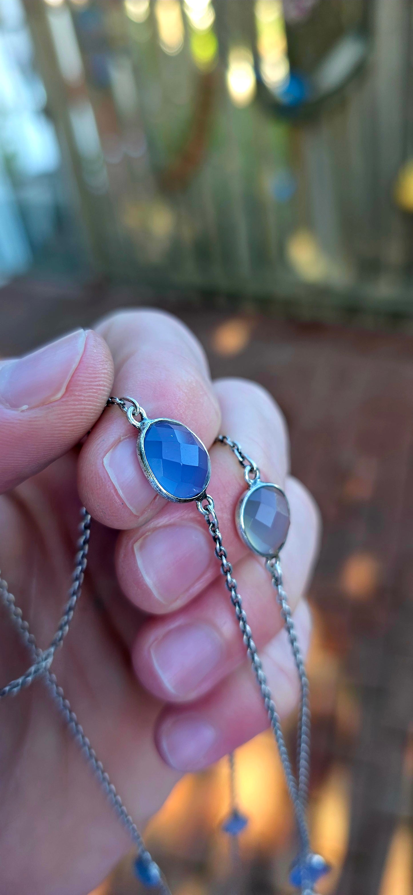 Extra-length sterling silver station-style necklace featuring a delicate scattering of faceted chalcedony gemstones gracefully suspended between fine sterling silver chain links.