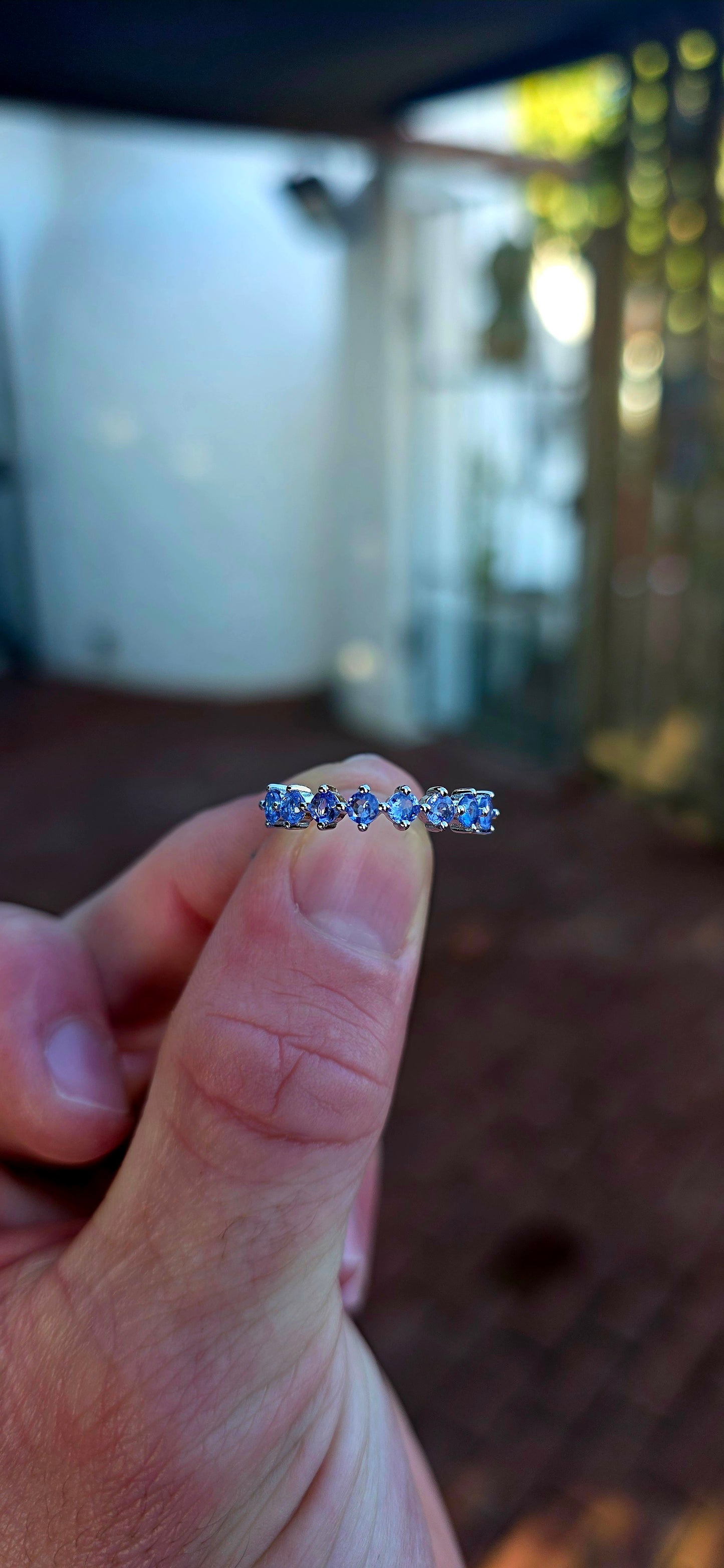 Lovely sterling silver half-eternity stacking ring, prong set with 7 faceted round-cut tanzanite gemstones in the most dreamy soft violet-blue hues.