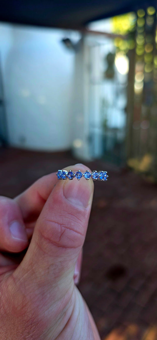 Lovely sterling silver half-eternity stacking ring, prong set with 7 faceted round-cut tanzanite gemstones in the most dreamy soft violet-blue hues.