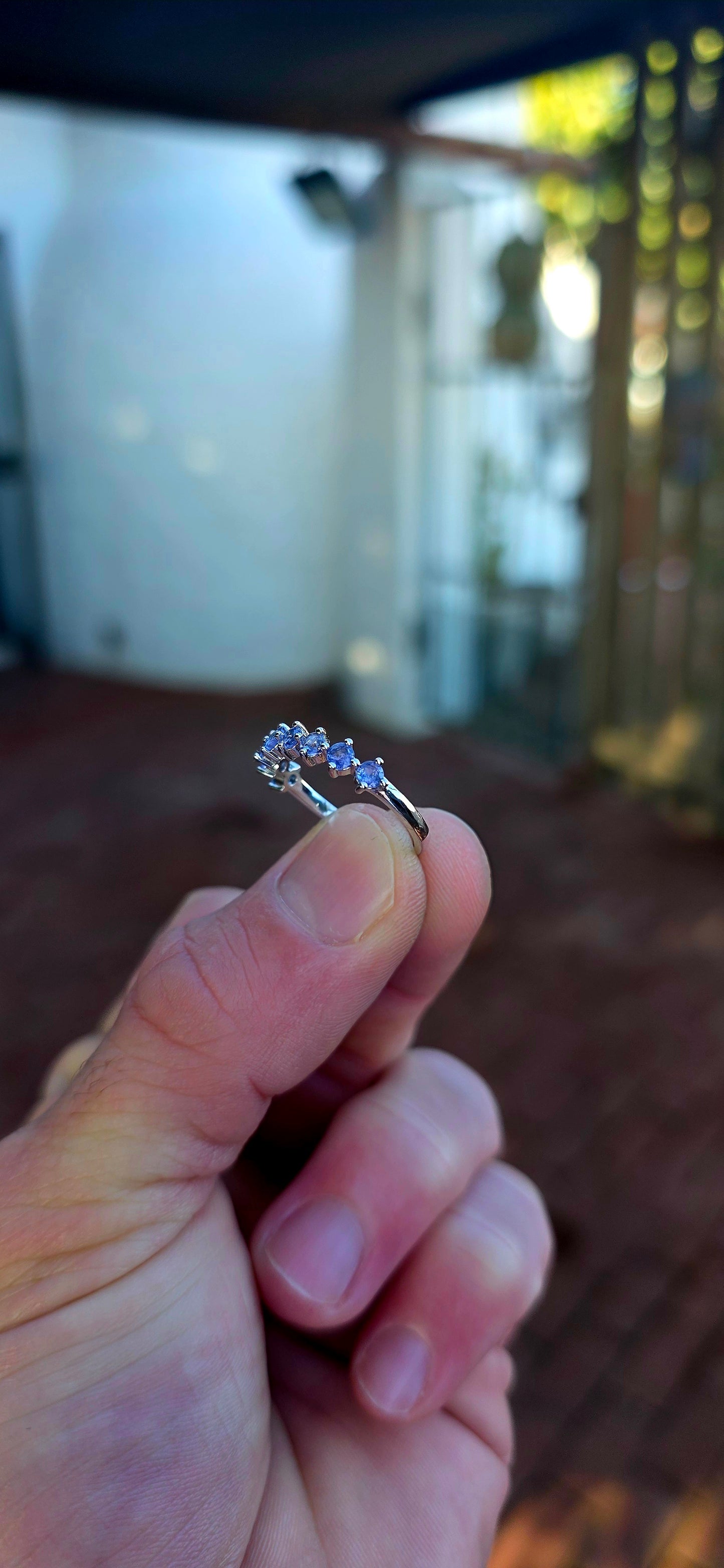 Lovely sterling silver half-eternity stacking ring, prong set with 7 faceted round-cut tanzanite gemstones in the most dreamy soft violet-blue hues.