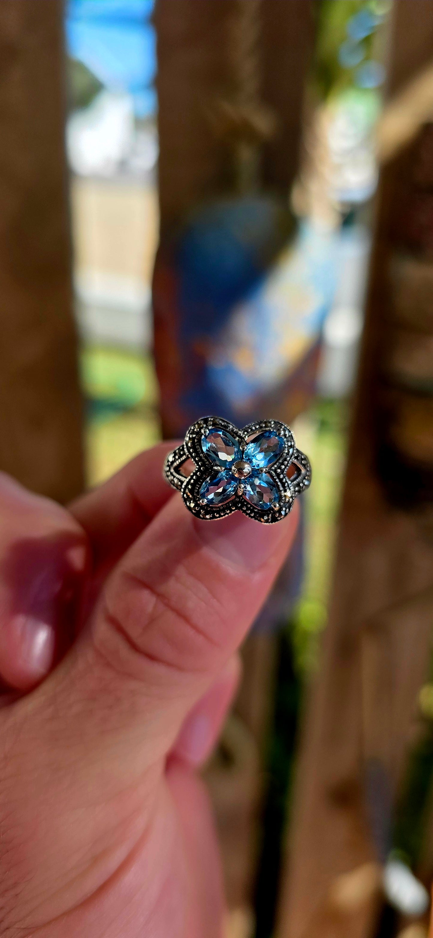 Enchanting sterling silver vintage revival dress ring featuring four pear-cut sky blue topaz gemstones arranged in the shape of a delicate flower.