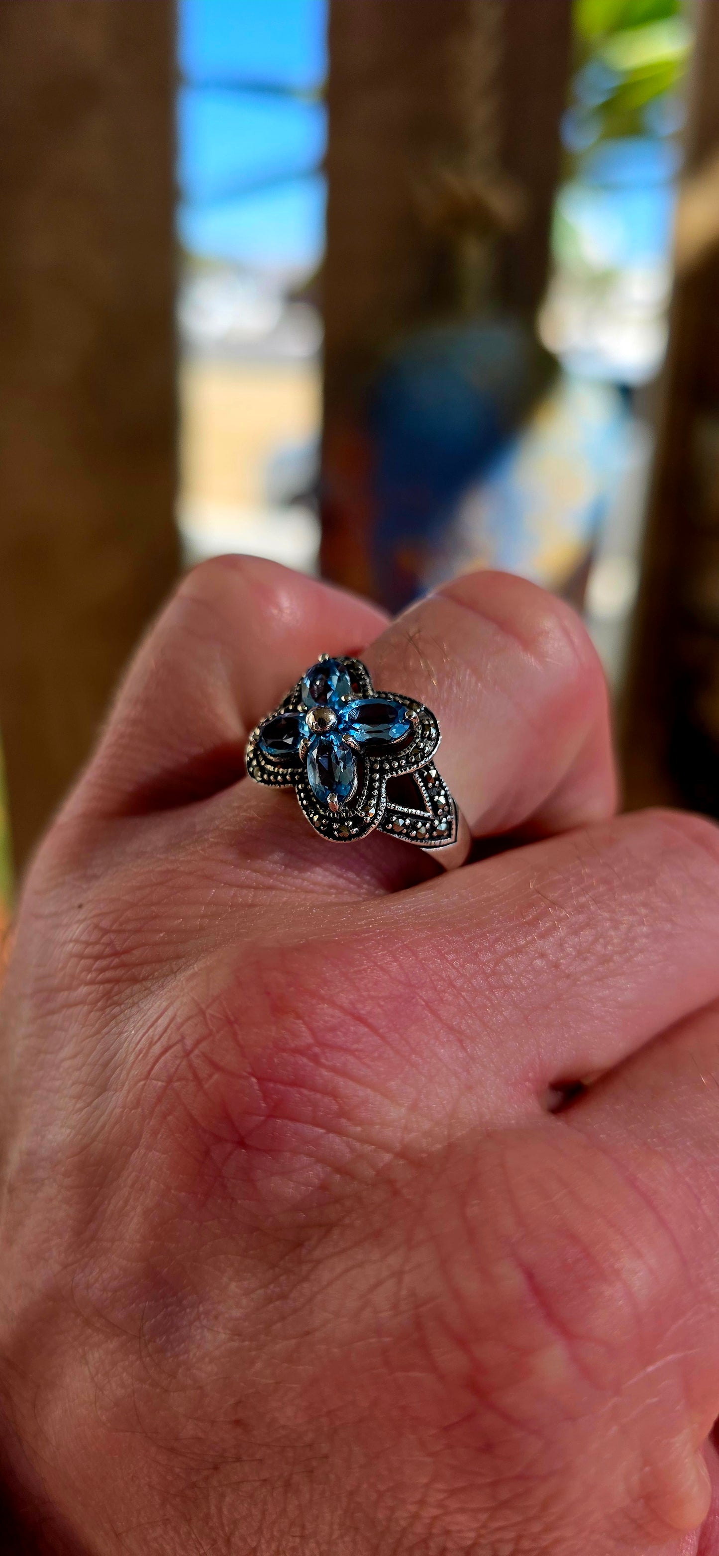 Enchanting sterling silver vintage revival dress ring featuring four pear-cut sky blue topaz gemstones arranged in the shape of a delicate flower.