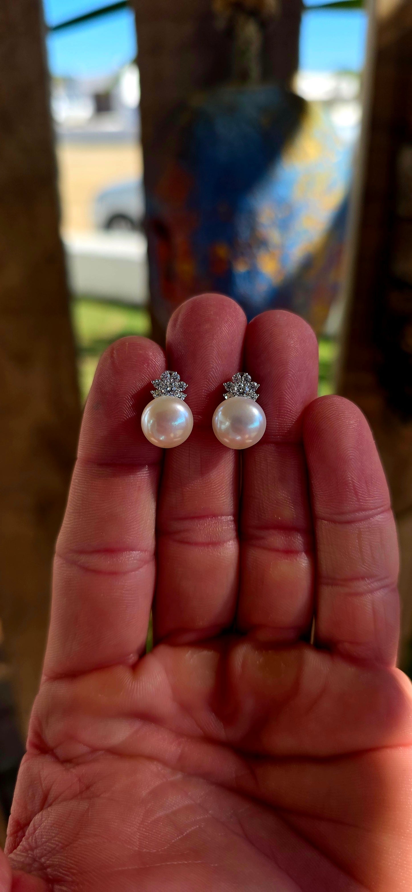 Beautiful luminous freshwater pearl stud earrings topped with delicate little crown motifs, each prong-set with sparkling round-cut cubic zirconia gemstones.