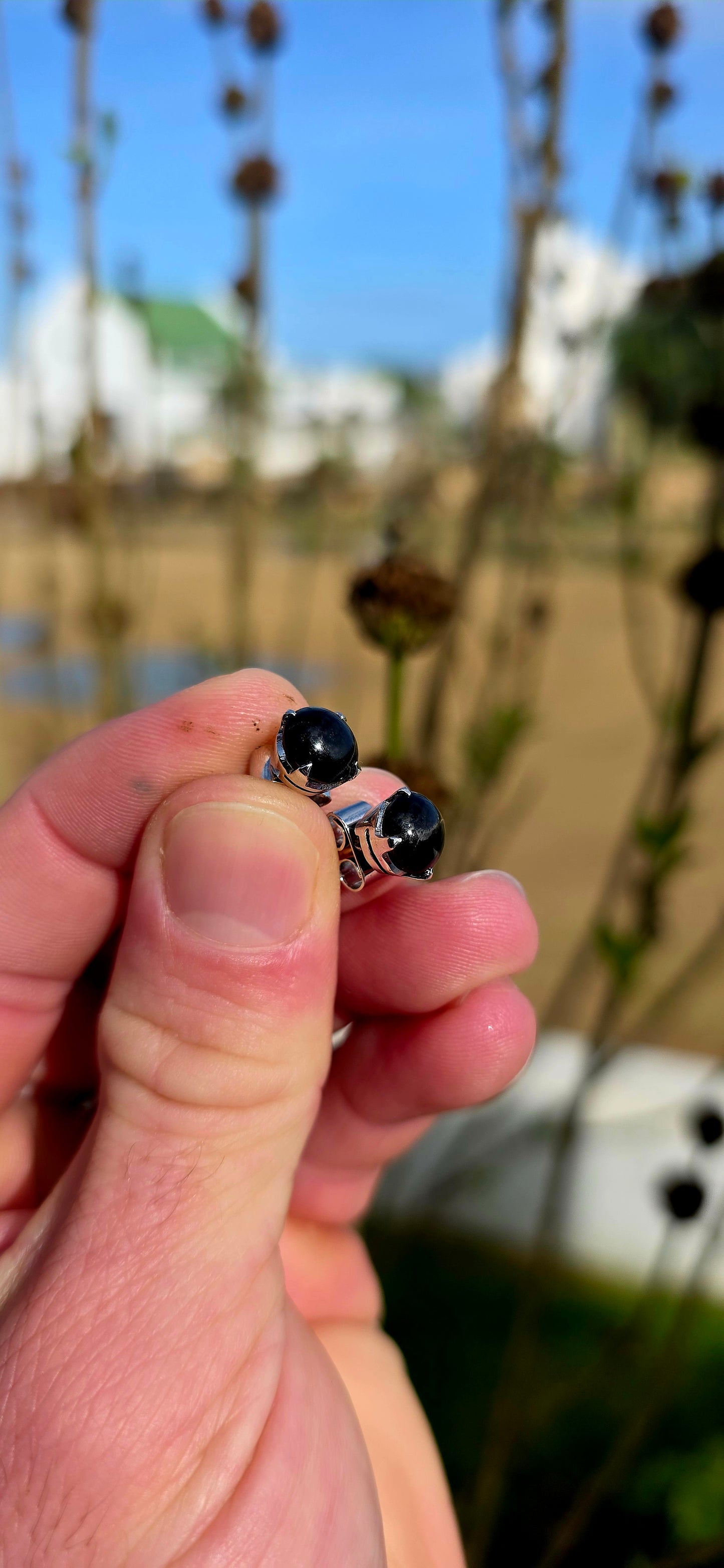 Unisex pair of sterling silver stud earrings with luxurious rhodium plating for a bright tarnish-resistant finish, each prong set with a genuine rare black star diopside cabochon gemstone.