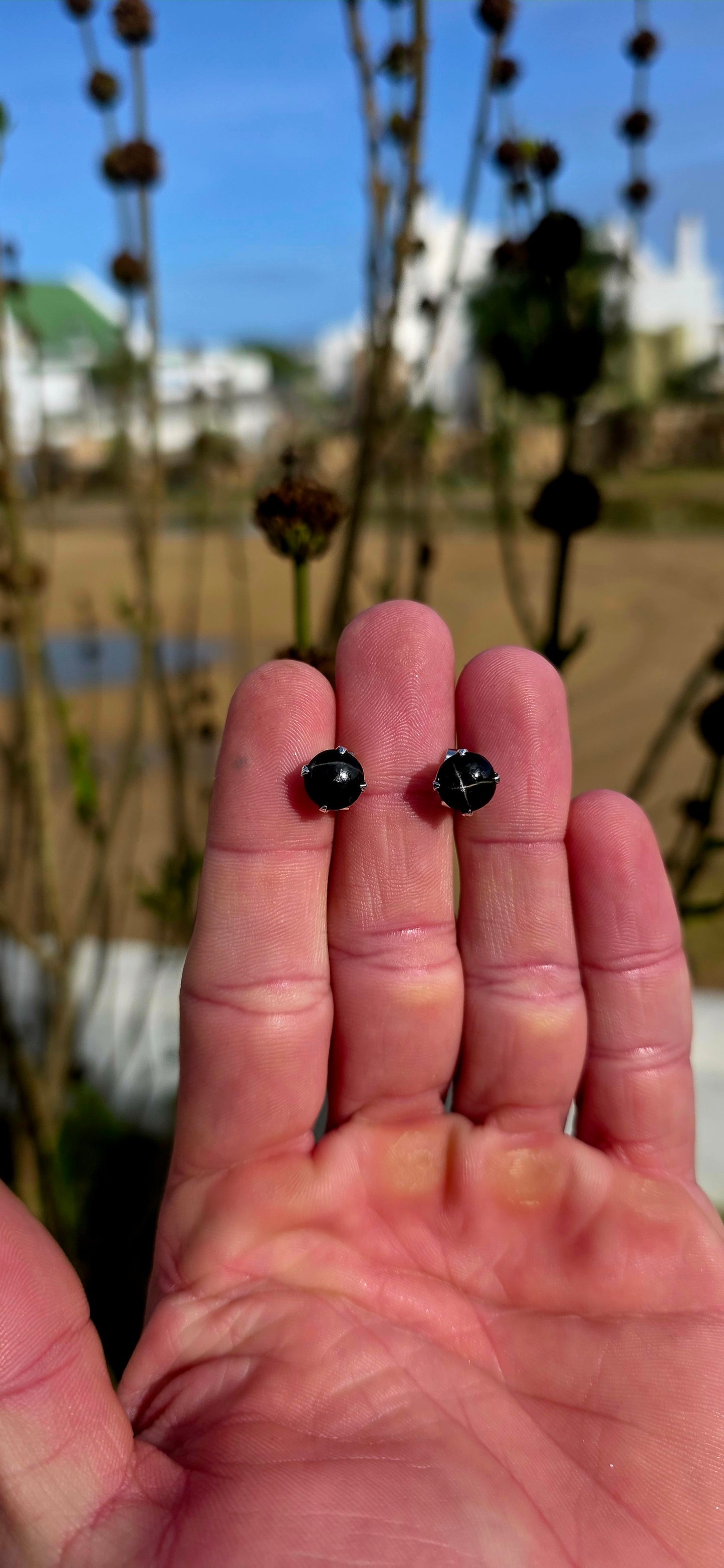 Unisex pair of sterling silver stud earrings with luxurious rhodium plating for a bright tarnish-resistant finish, each prong set with a genuine rare black star diopside cabochon gemstone.