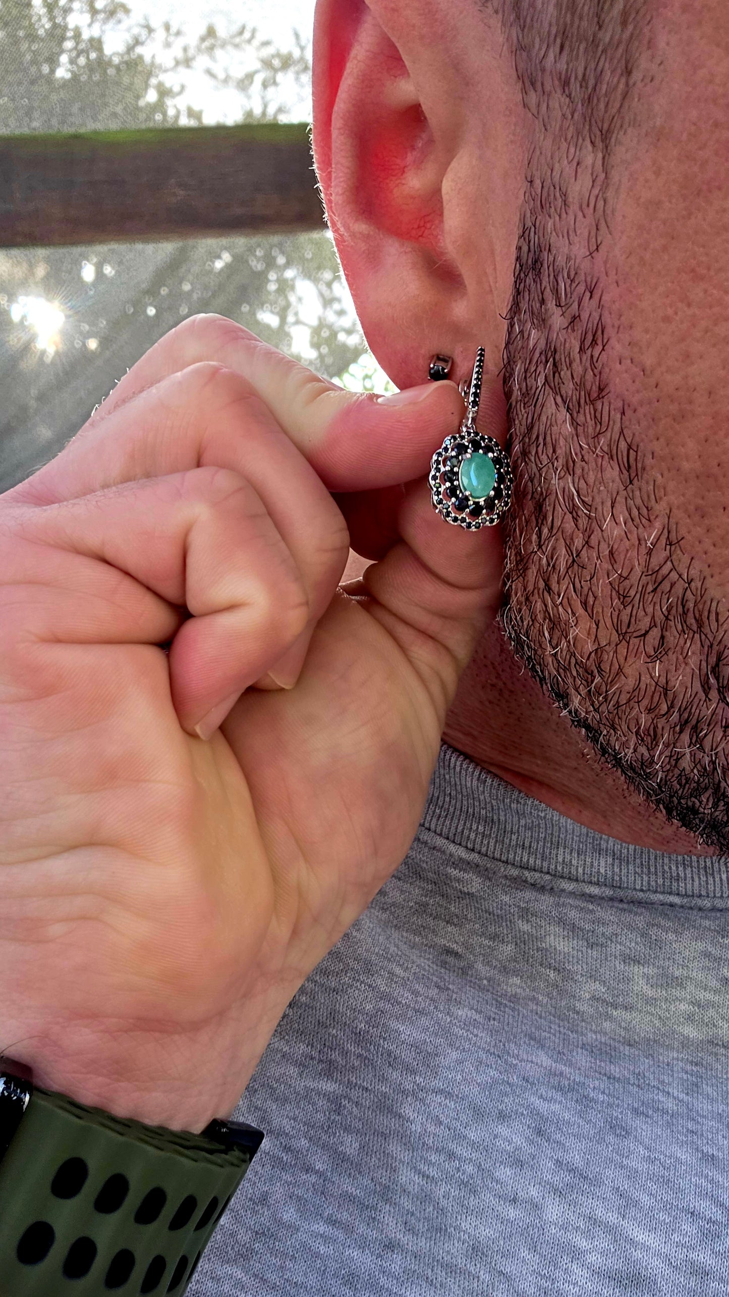 Beautiful matching sterling silver floral-inspired ring and earring set featuring luminous oval-cut emerald gemstones at their centres, each delicately prong set and framed in dramatic double scalloped halos of sparkling black spinel gemstones.