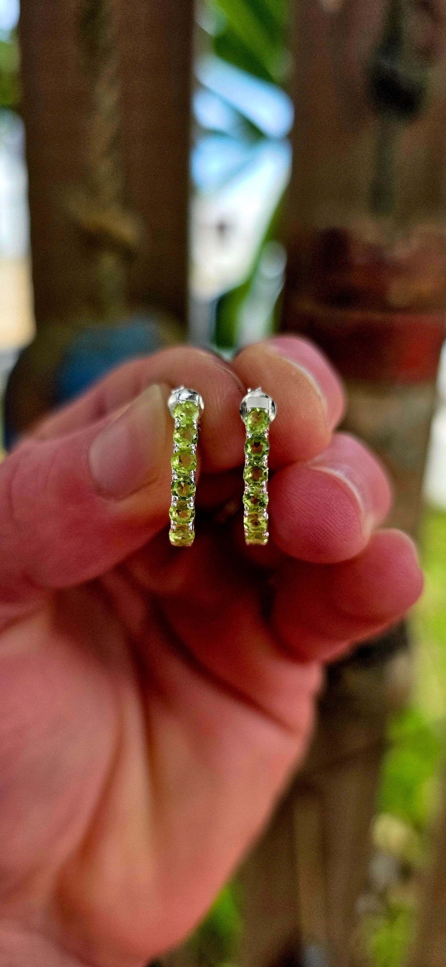 These beautiful sterling silver half hoop “J” shaped earrings are prong set with a shimmering line-up of round-cut peridot gemstones, glowing in vibrant shades of fresh lime, apple green, and soft golden-green sparkle.