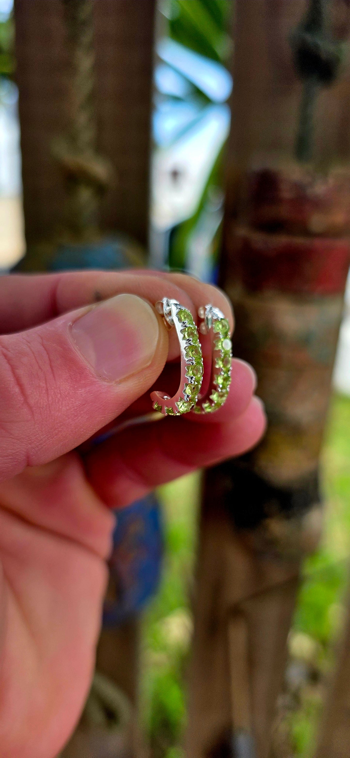These beautiful sterling silver half hoop “J” shaped earrings are prong set with a shimmering line-up of round-cut peridot gemstones, glowing in vibrant shades of fresh lime, apple green, and soft golden-green sparkle.