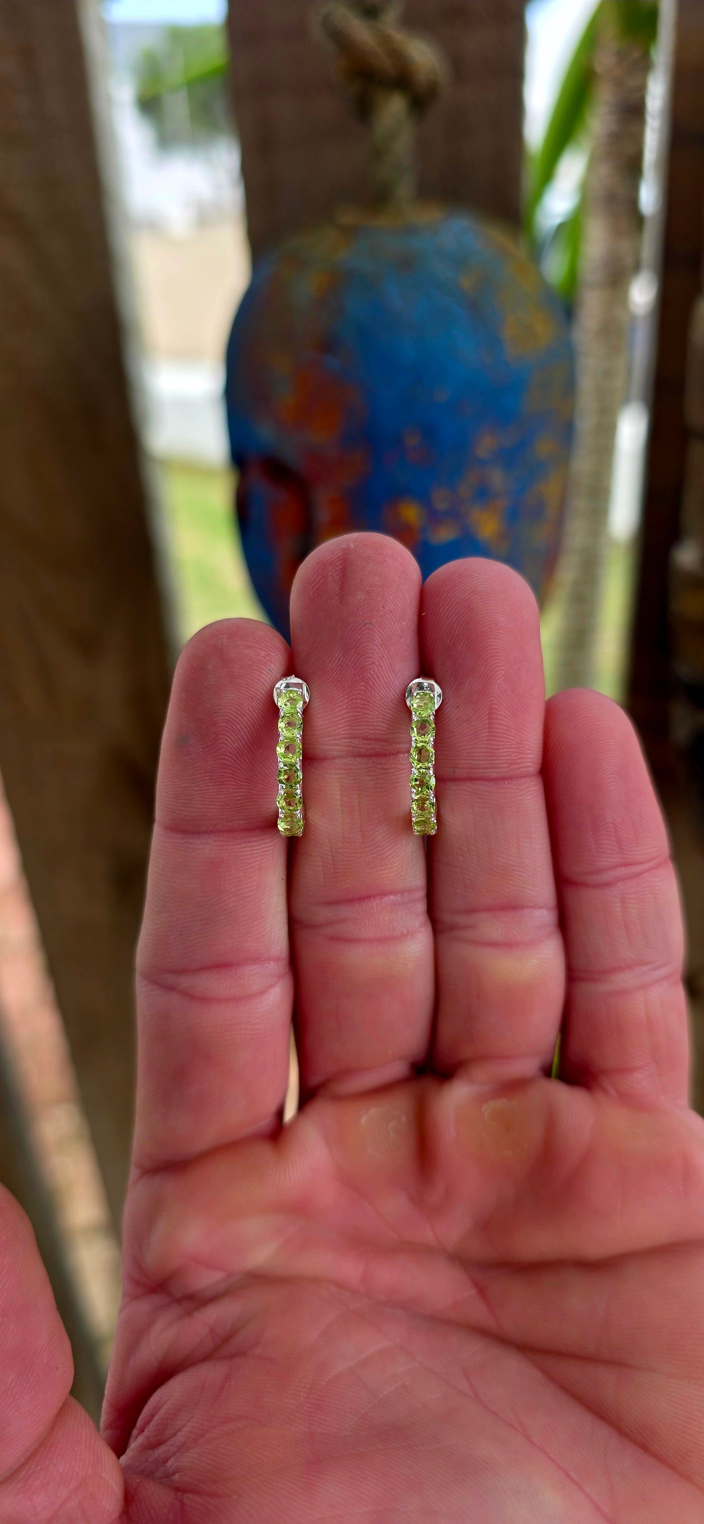 These beautiful sterling silver half hoop “J” shaped earrings are prong set with a shimmering line-up of round-cut peridot gemstones, glowing in vibrant shades of fresh lime, apple green, and soft golden-green sparkle.