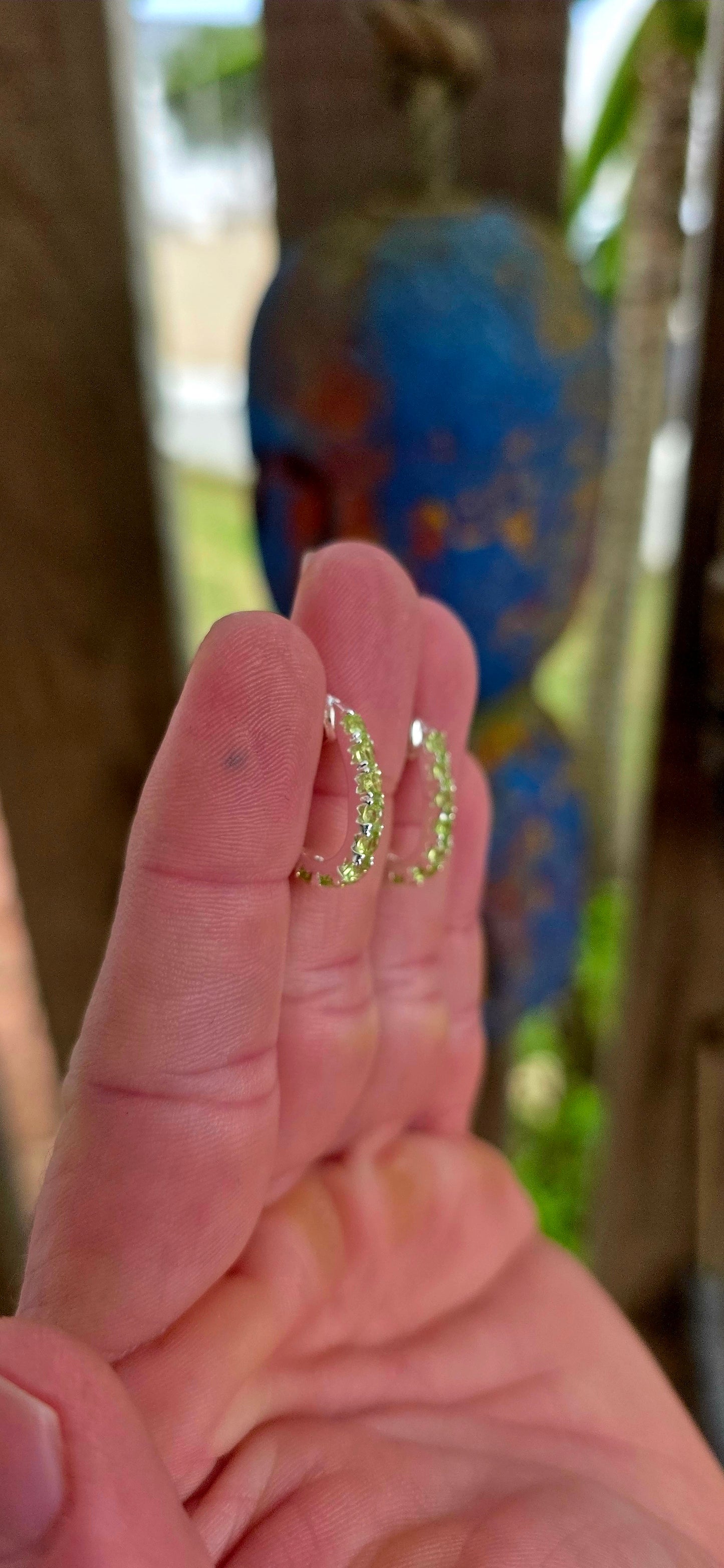 These beautiful sterling silver half hoop “J” shaped earrings are prong set with a shimmering line-up of round-cut peridot gemstones, glowing in vibrant shades of fresh lime, apple green, and soft golden-green sparkle.