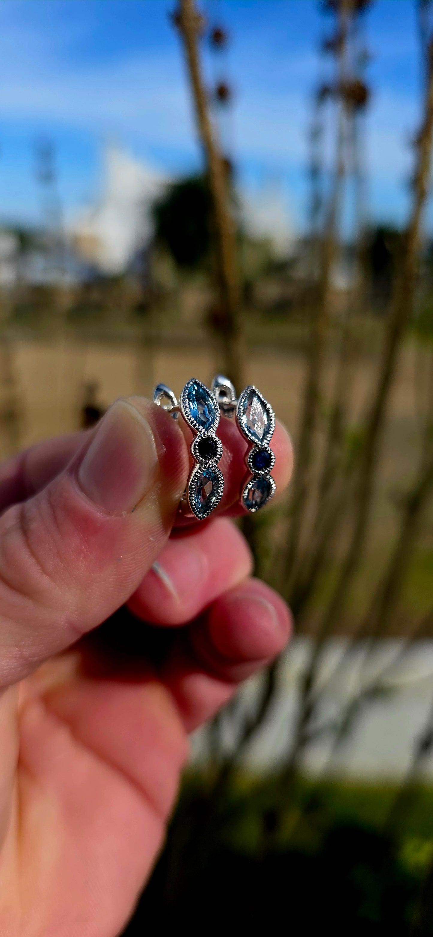 Crafted in sterling silver, these beautiful half-hoop dress earrings feature a graceful vertical arrangement of faceted marquise-cut sky blue topaz gemstones, separated by a rich dark blue round-cut sapphire at the centre.