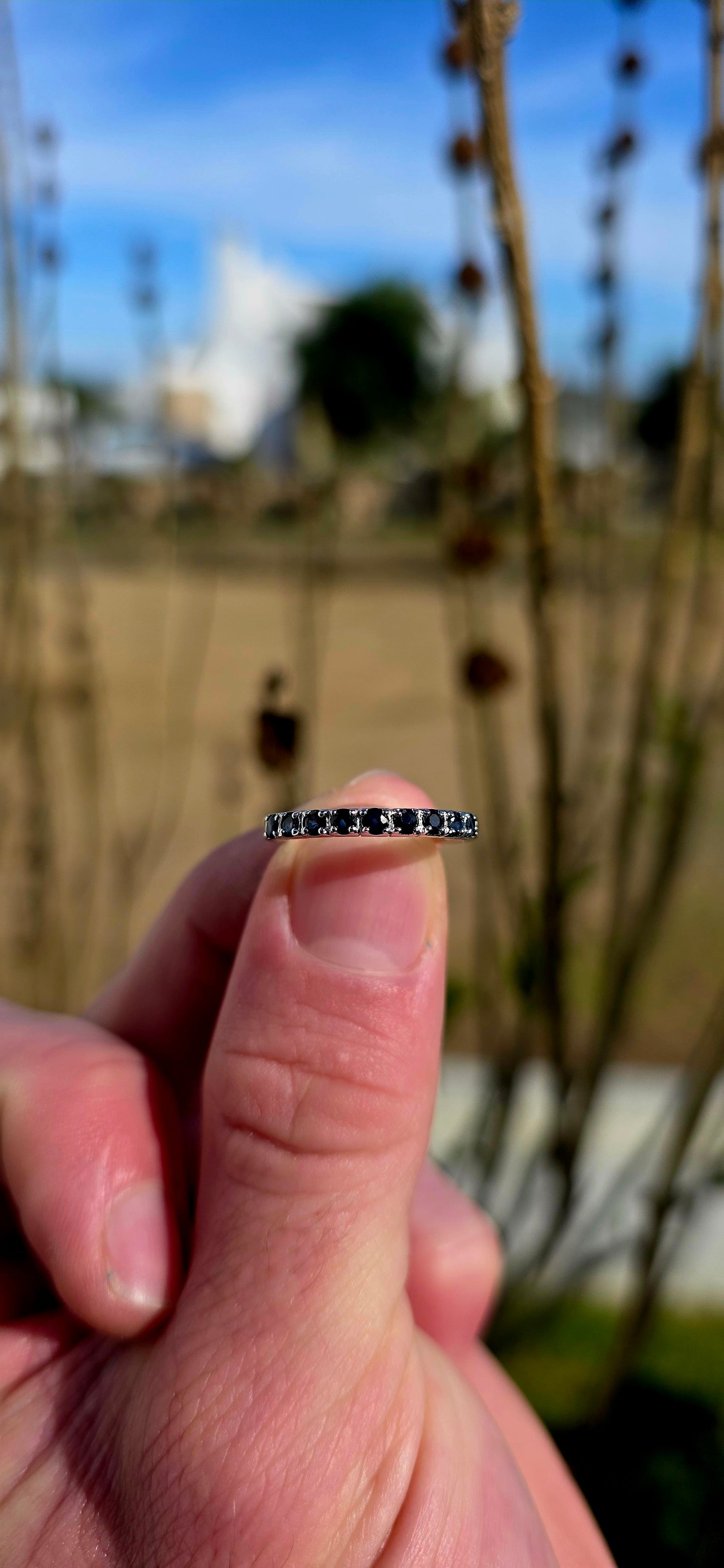 Crafted in sterling silver, this dainty stacking ring is beautifully set with nine round-cut blue sapphires in a delicate combination of prong and flush-style settings.
