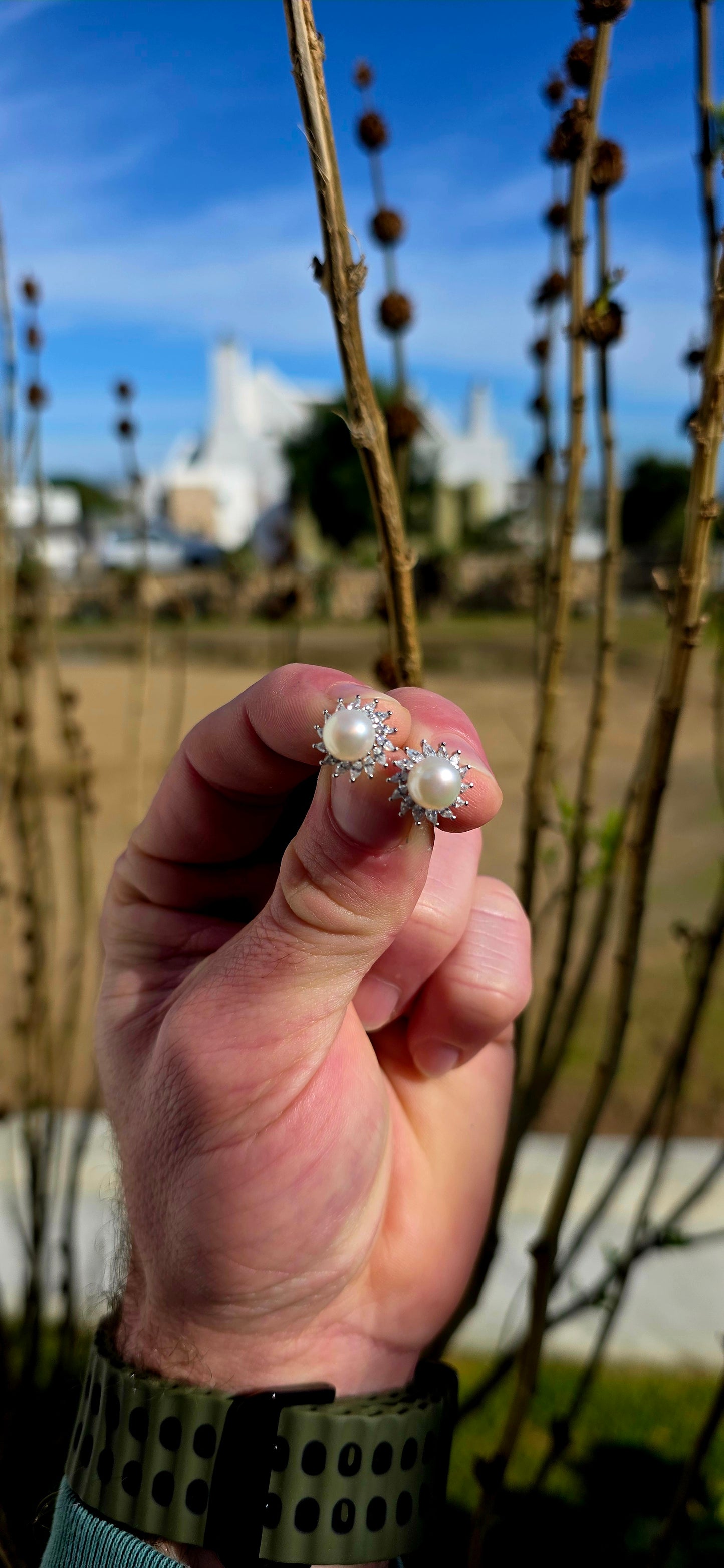 These elegant and beautifully classic sterling silver stud earrings each feature a luminous freshwater pearl at the centre, framed in a radiant halo of marquise-cut cubic zirconia gemstones in delicate prong settings.