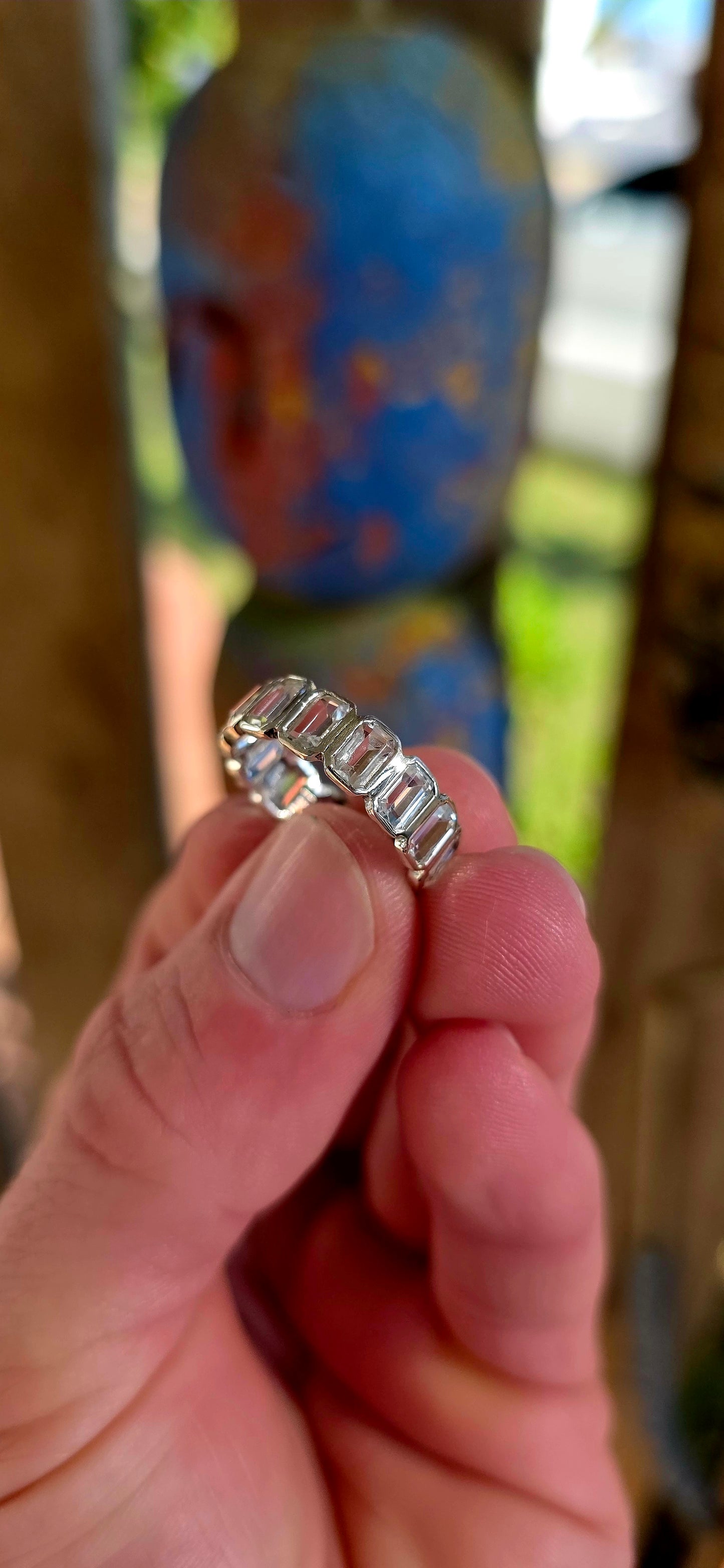 A truly breathtaking sterling silver full eternity ring, shimmering with fourteen emerald-cut white topaz gemstones set continuously all the way around the band in sleek tube settings.