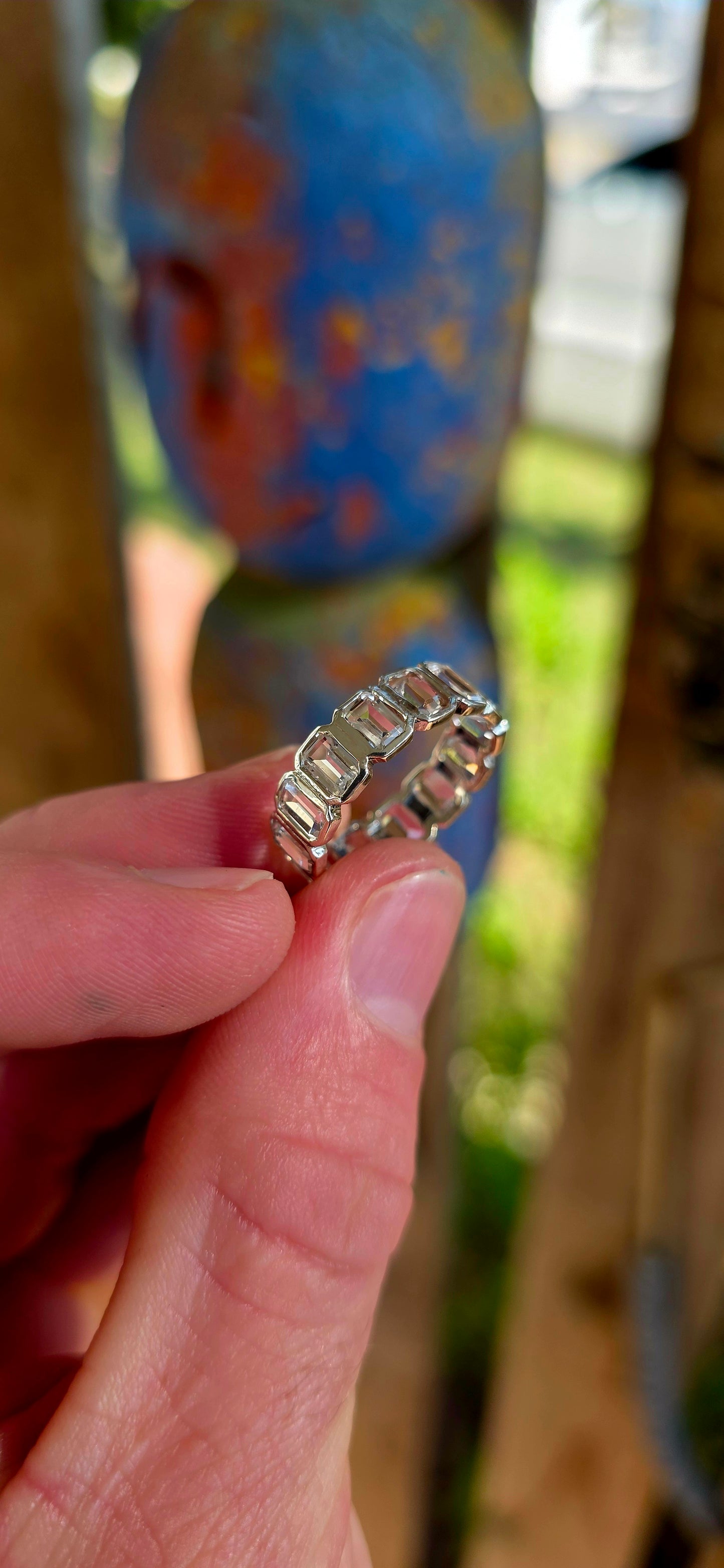 A truly breathtaking sterling silver full eternity ring, shimmering with fourteen emerald-cut white topaz gemstones set continuously all the way around the band in sleek tube settings.